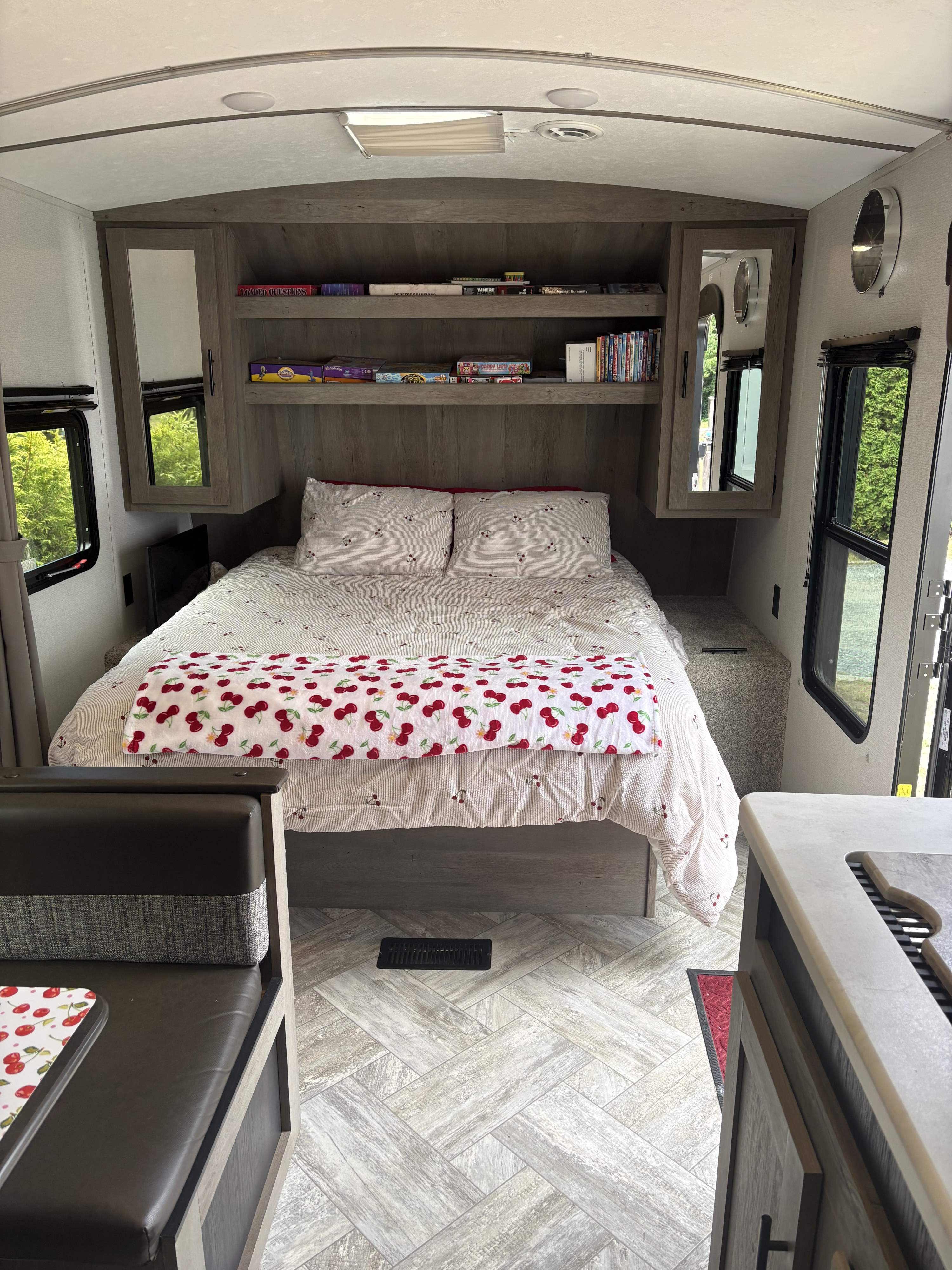 RV rental interior featuring a cozy bedroom with cherry bedding, board games, and a dinette.. Keystone RV Springdale 2021