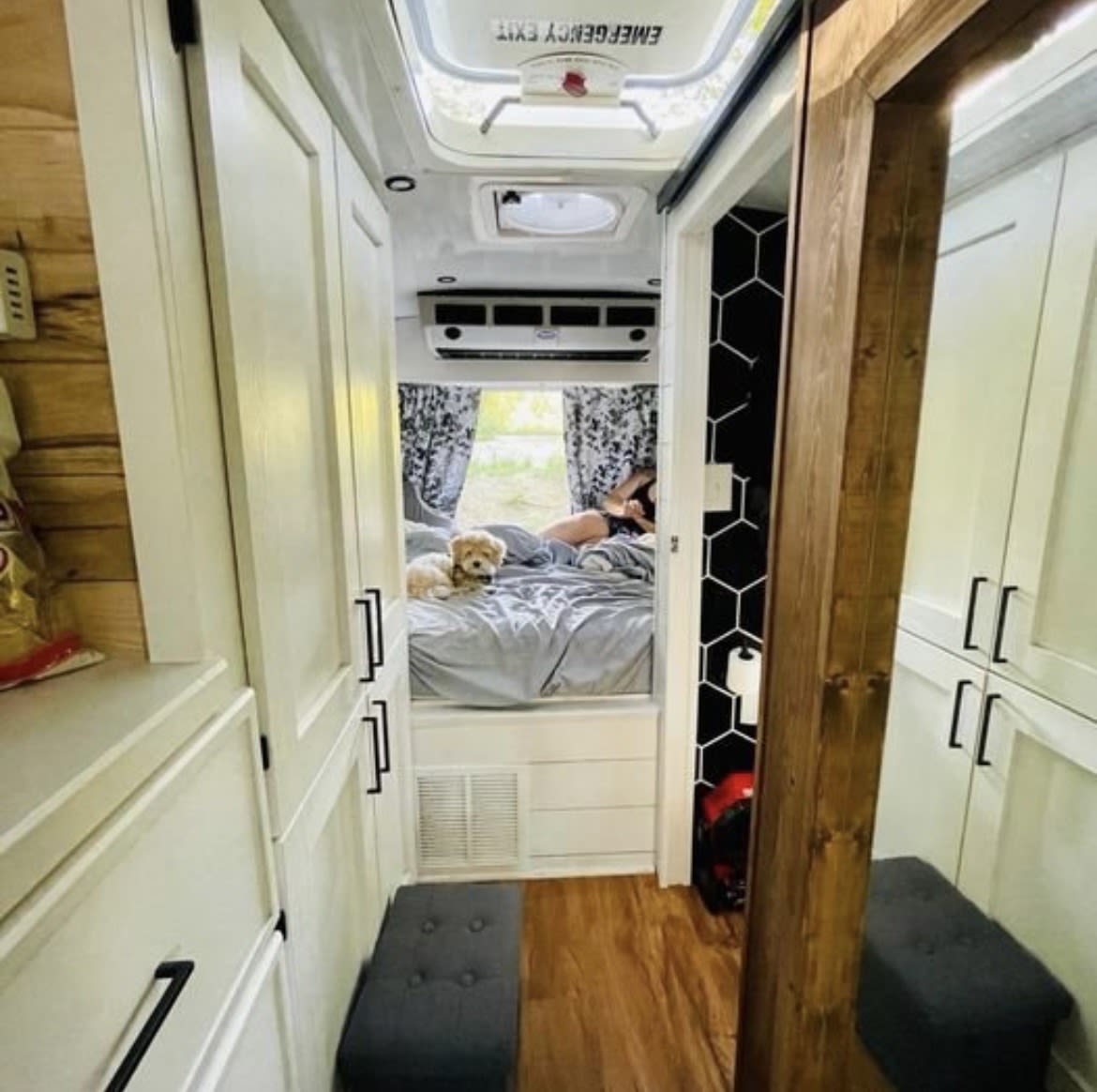 This cozy RV rental features a compact bedroom with a person and dog on the bed, smart storage, and seating.. Chevy C4500 Kodiak 2008