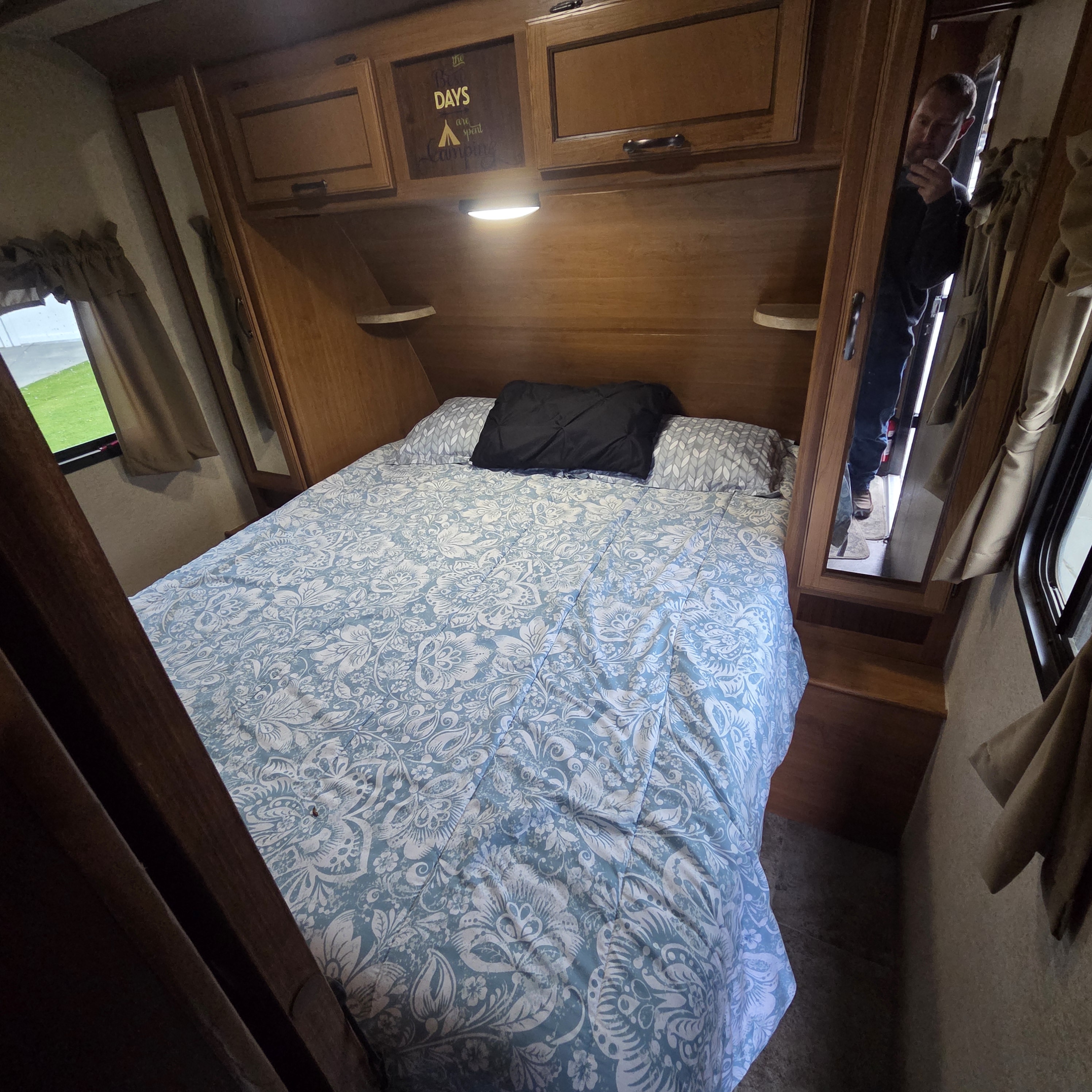 Cozy RV rental bedroom with a patterned bed, storage, and a "Best Days are spent Camping" sign.. Crossroads RV Sunset Trail Super Lite 2016