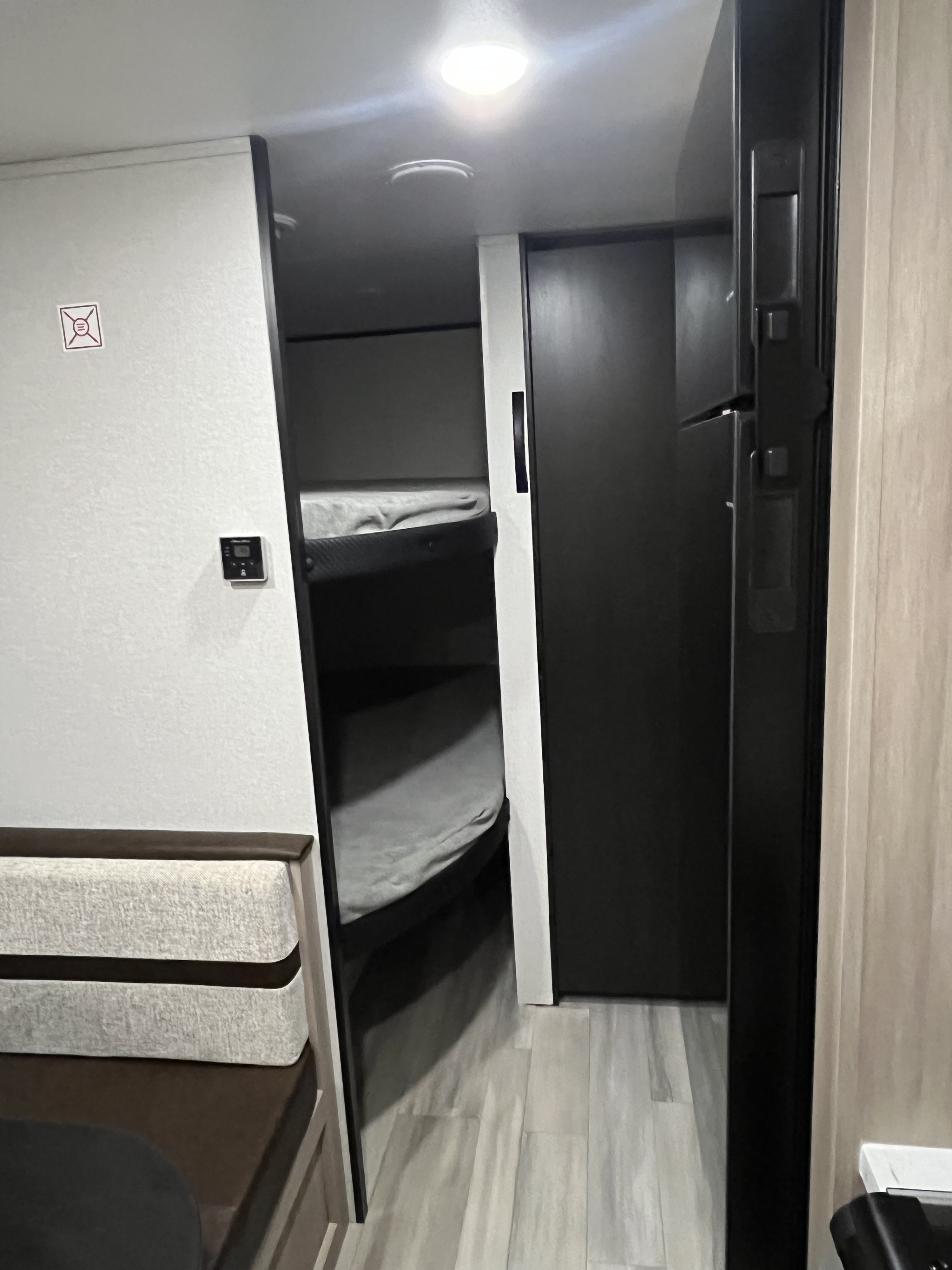 RV rental interior features bunk beds, a dinette seat, wall-mounted thermostat, and a black refrigerator.. Heartland TT 2026