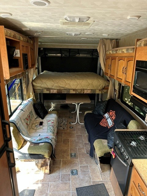 Spacious RV rental interior with a raised bed, dual sofas, kitchenette, and tiled floor, perfect for adventurous travel.. Forest River Puma 2011