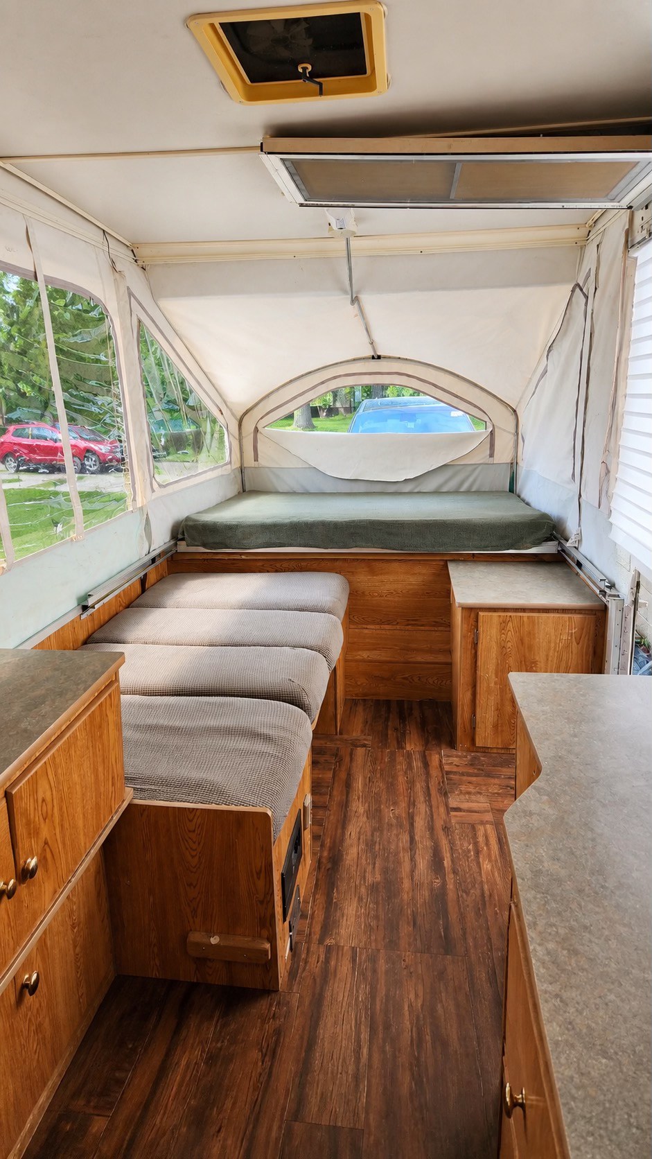 Cozy pop-up rv rental interior with a bed, dinette seating, wood-grain floor, and bright windows. Ideal for your next trip.. Viking 1906 2001