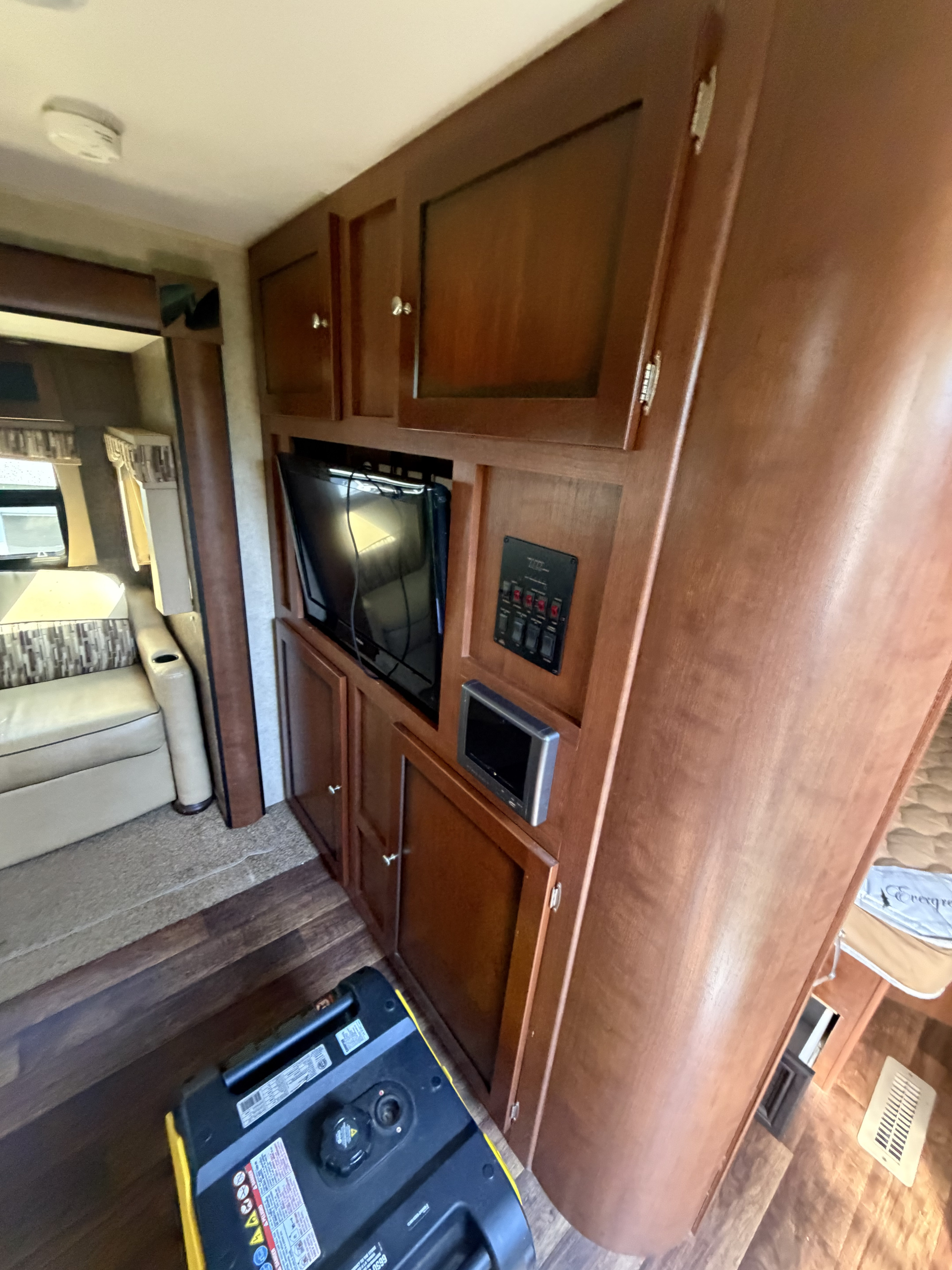 RV rental interior featuring a TV, control panel, wood cabinets, cozy seating, and a portable generator on the floor.. Dutchmen Kodiak 2012