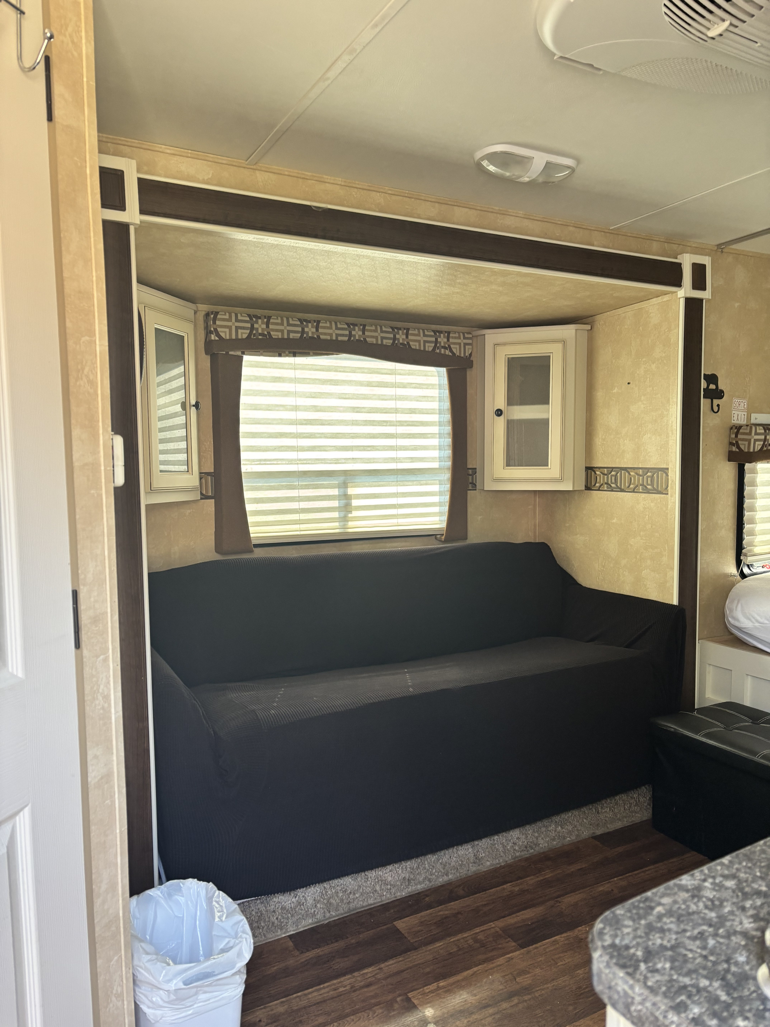 Experience a cozy RV rental: sofa, window with blinds, and overhead cabinets in a well-lit slide-out area.. Cruiser RV Fun Finder 2013