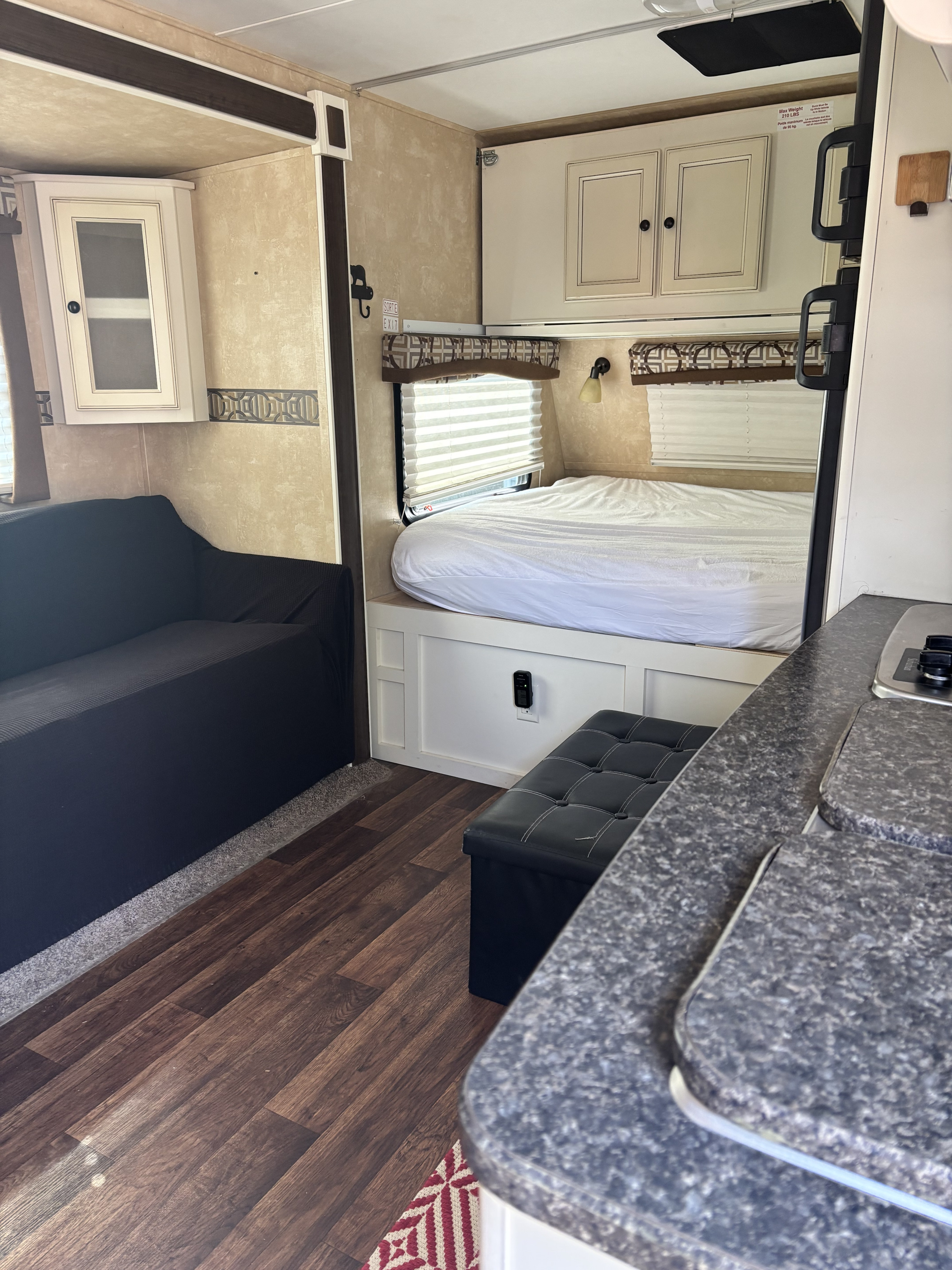 Cozy RV rental interior featuring a bed, dark sofa, kitchen counter, and ample storage for comfortable travel.. Cruiser RV Fun Finder 2013