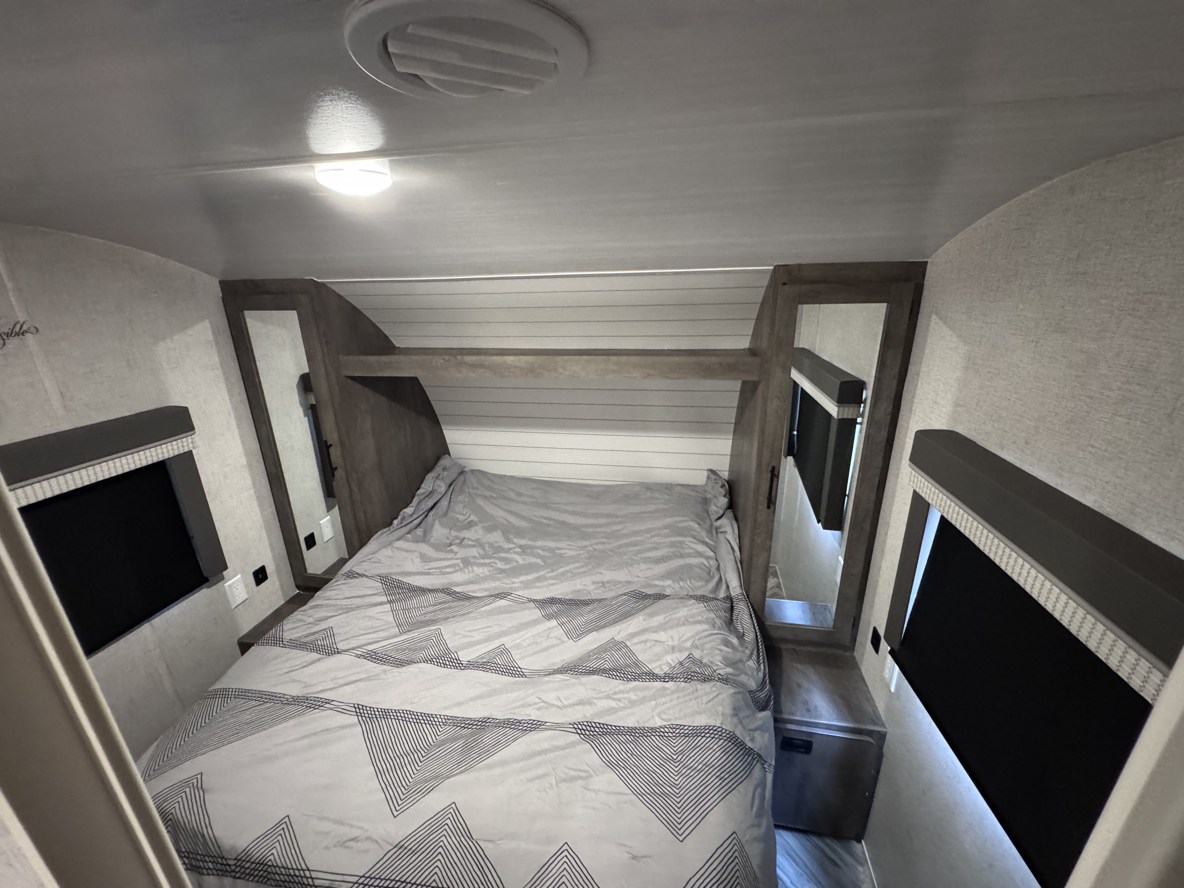 RV rental bedroom interior featuring a comfy bed with patterned comforter, window shades, and built-in storage. Ready for your adventure.. Forest River Salem Cruise Lite 2022