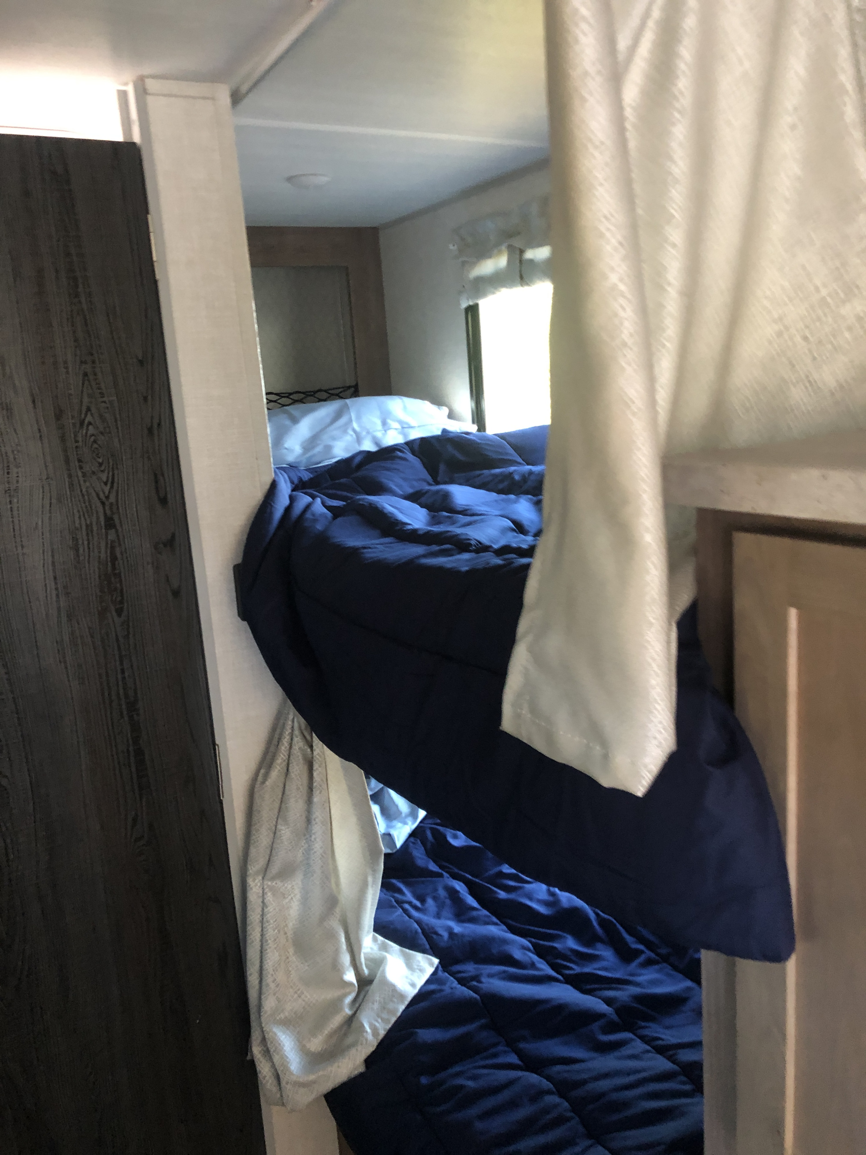 Cozy rv rental bunk beds with navy bedding and white pillows, providing comfortable sleeping space inside a camper.. Forest River No Boundaries 19.7 2021