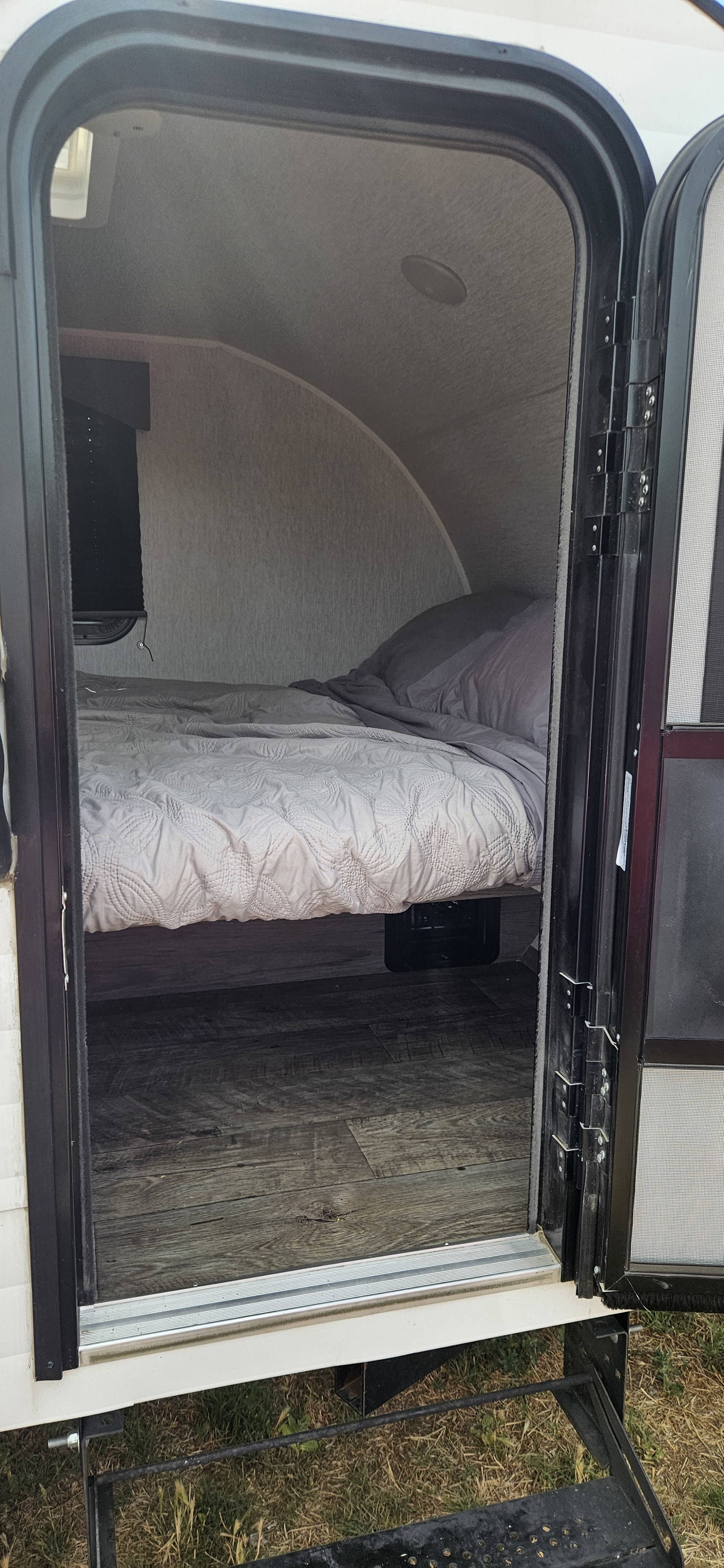RV rental bedroom: Small, cozy interior with a bed, light comforter, and curved walls, viewed from the doorway.. Sunset Park RV SunRay 2024
