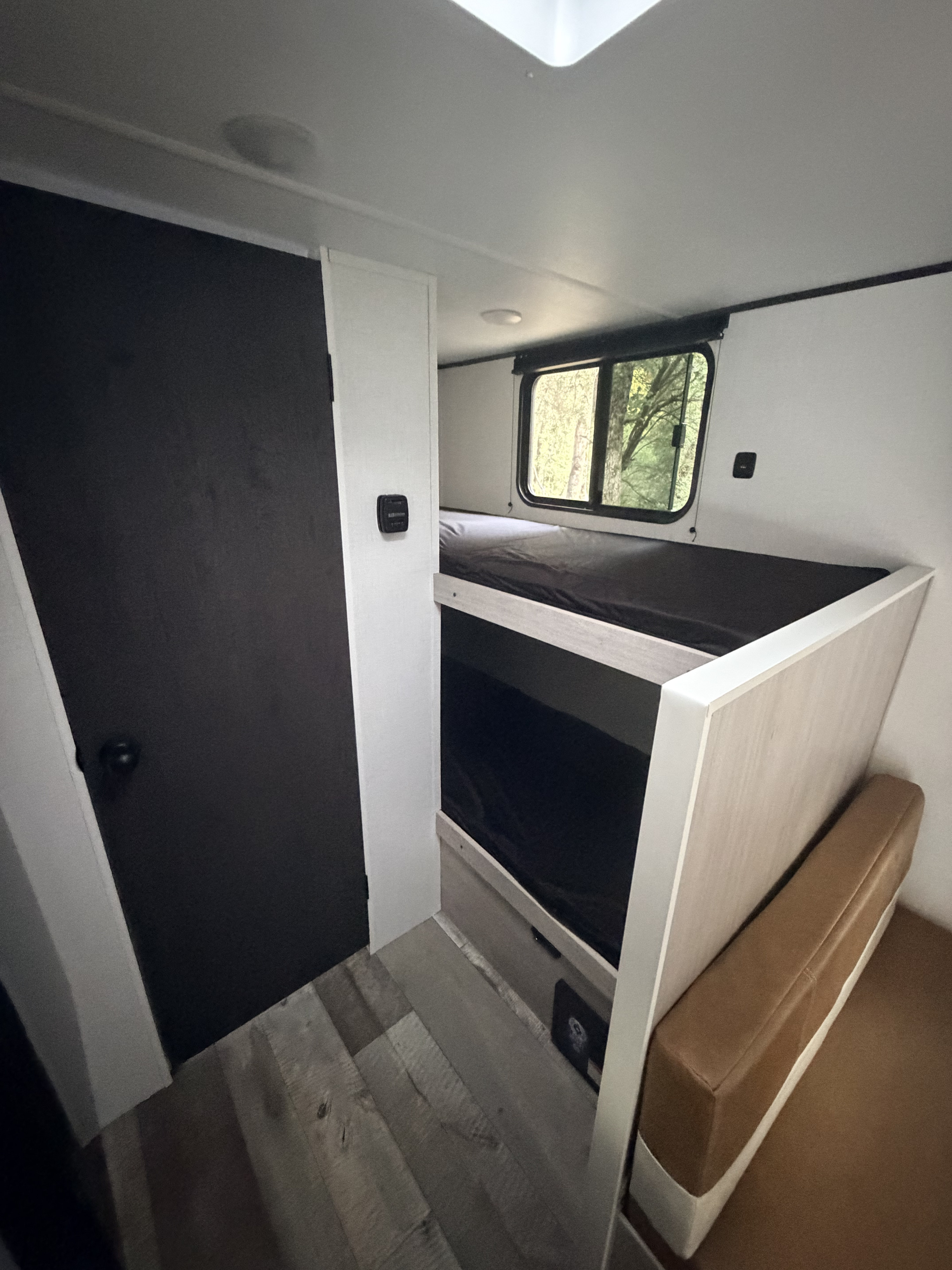 Cozy RV rental interior featuring bunk beds, a nature-view window, and a comfortable bench. Perfect for travel adventures!. Keystone RV Crossrads Zinger 18BH 2026