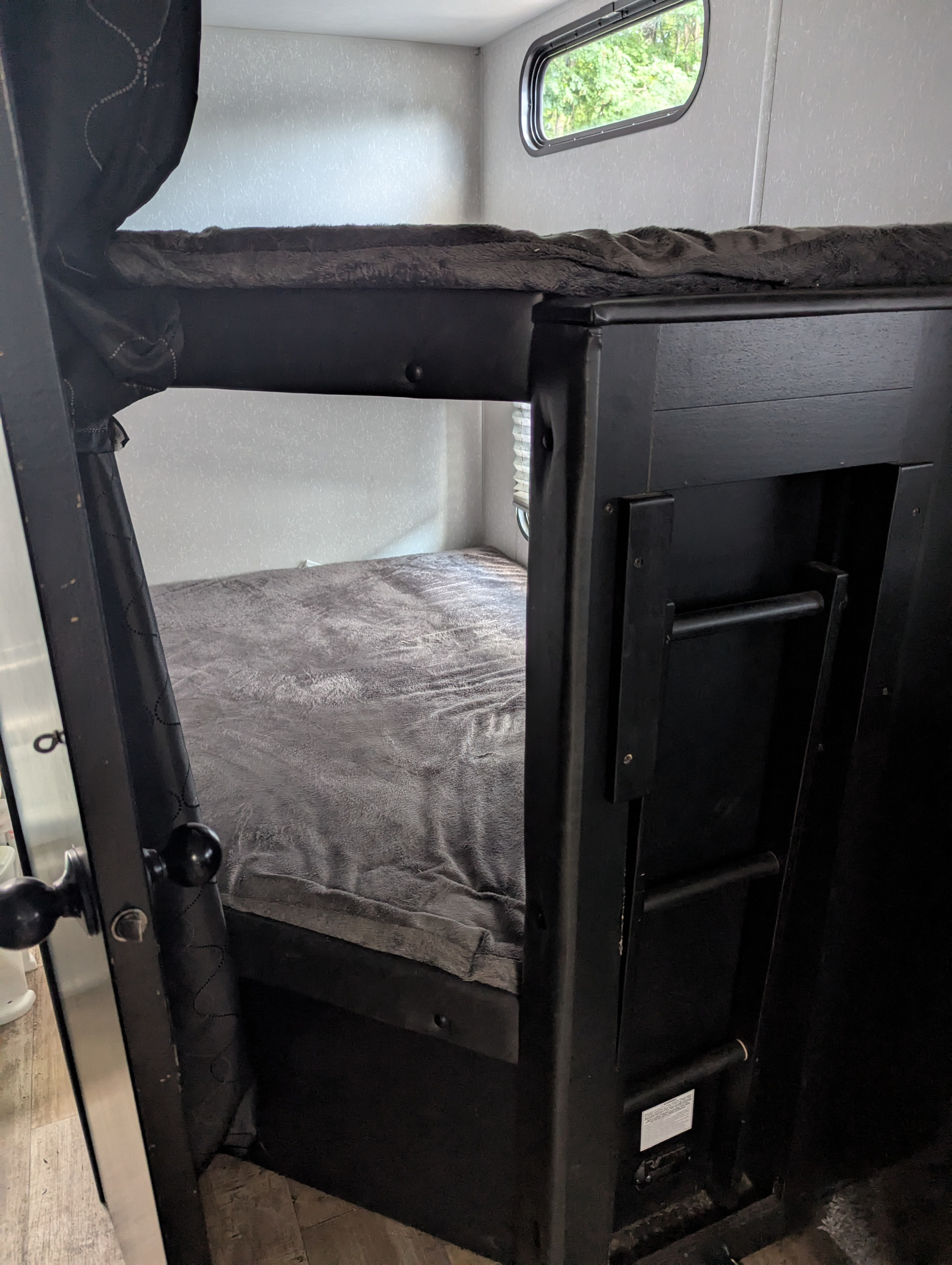 RV rental bunk beds featuring a ladder, cozy gray blankets on the beds, and a window for natural light inside the camper.. Forest River Cherokee Grey Wolf 2021