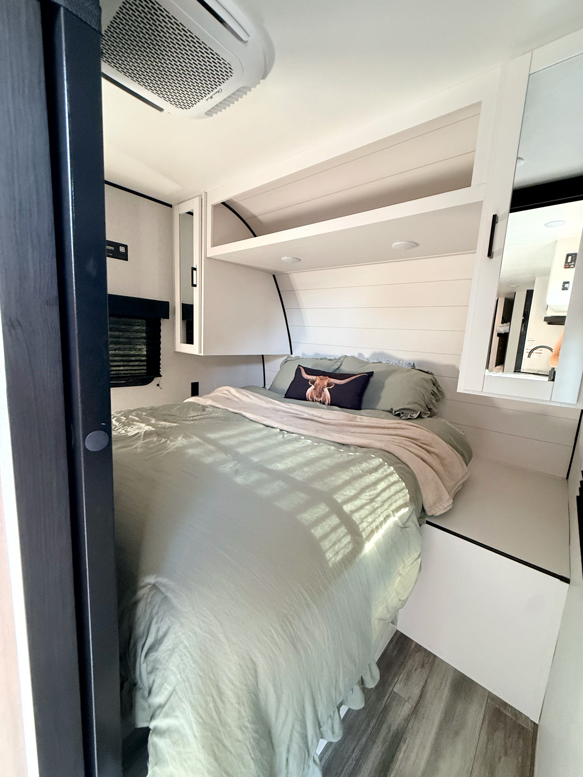 Bright RV rental bedroom with a bed, green bedding, longhorn pillow, white shiplap walls, and functional overhead storage.. Jayco Flight SLX 261BHS 2026