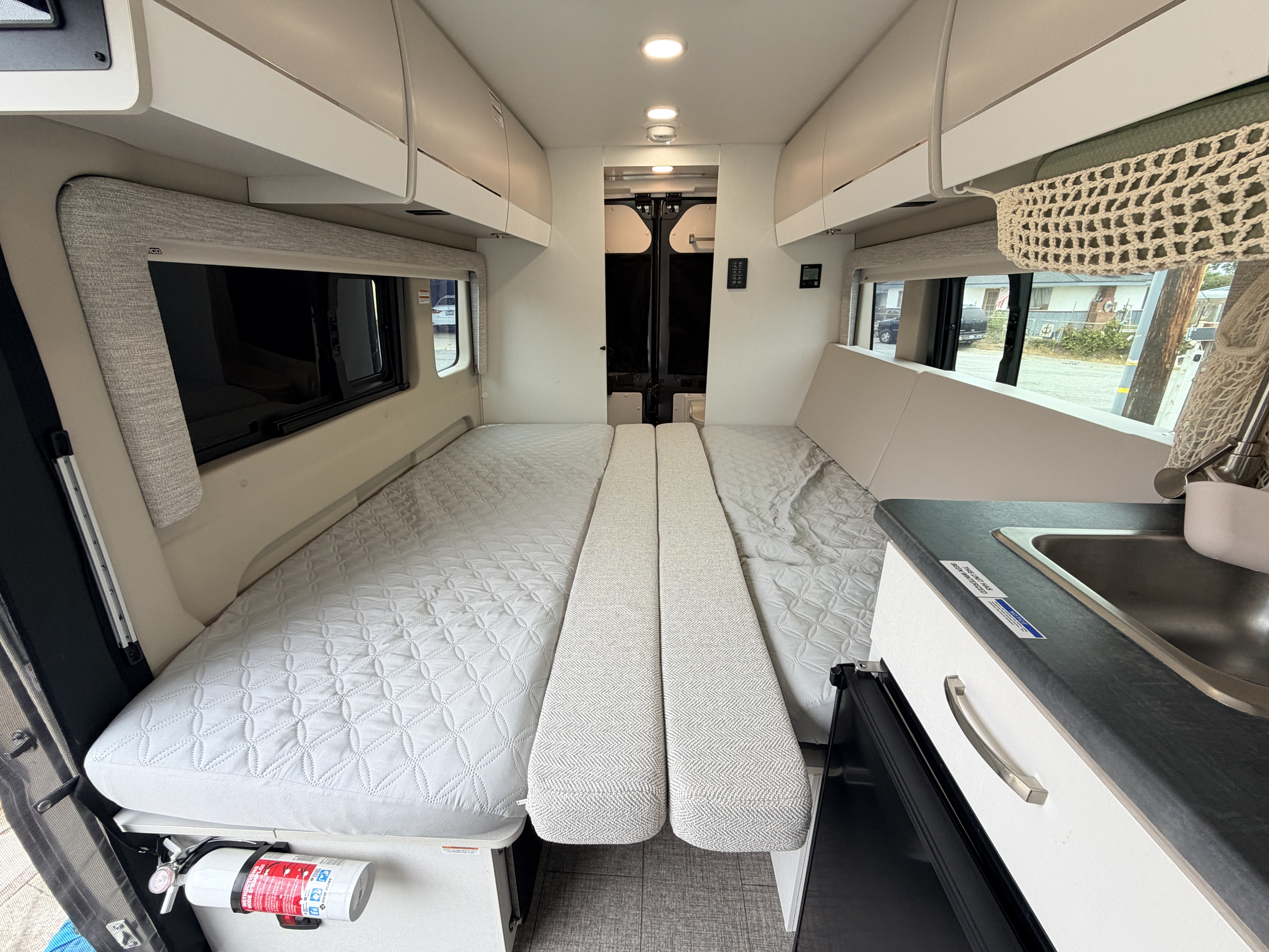Modern RV rental interior featuring convertible beds, compact kitchen, and overhead storage for a comfortable journey.. Jayco Swift 2025