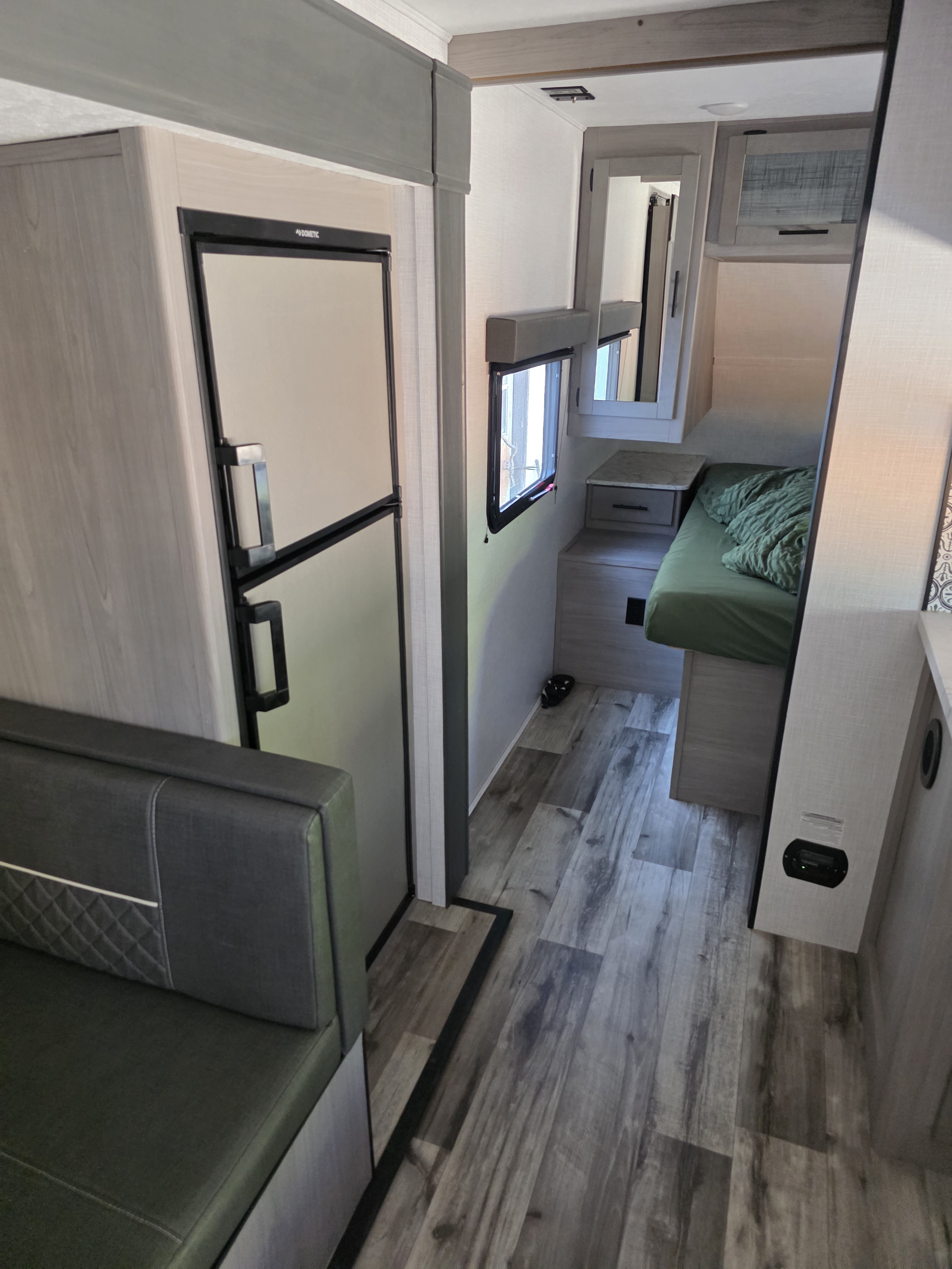RV rental interior. Left: refrigerator, dinette. Right: hallway to a bunk bed. Features light wood-look decor.. Dutchmen Coleman Light 2023