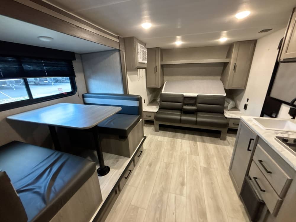This RV rental interior offers a dinette, a versatile sleeping area, and a compact kitchen for your travels.. Keystone RV Hideout Sport 2025