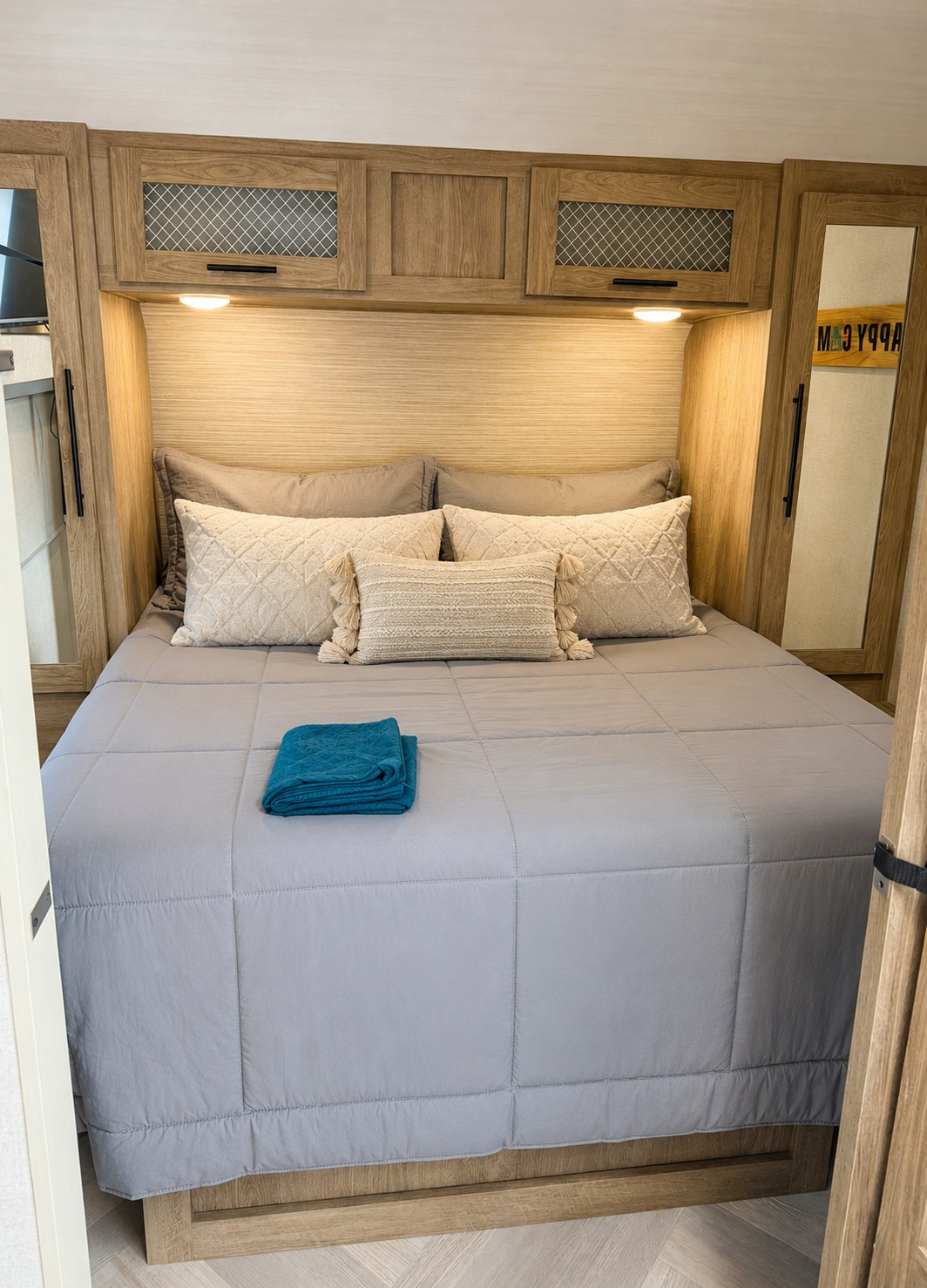 RV rental bedroom with a cozy bed, grey comforter, cream pillows, wood cabinets, and ambient lighting for comfortable travel.. Forest River Salem 2021