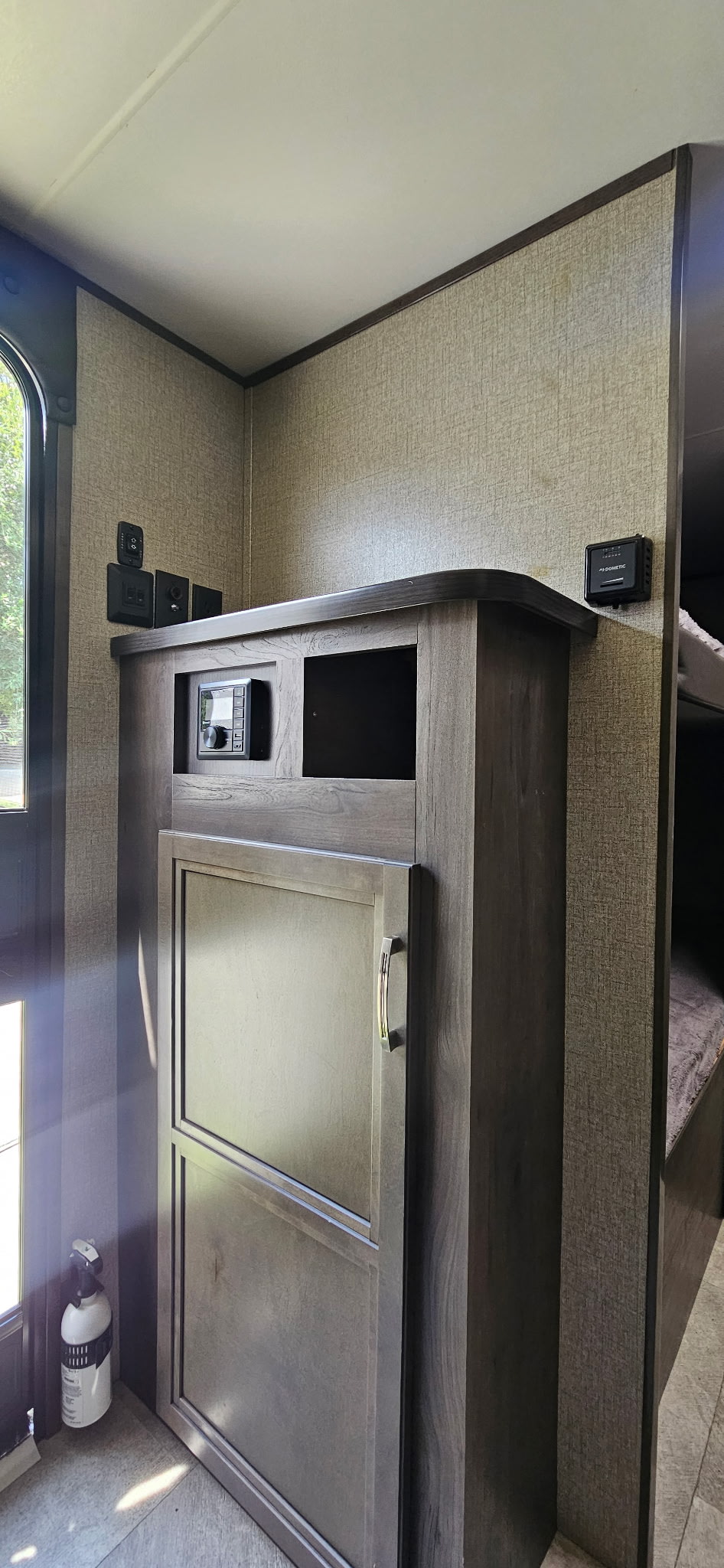 Modern rv rental interior with control panel, stereo, and Dometic thermostat. Shows wood cabinetry and bunk bed area.. Jayco Jay Flight SLX 2020