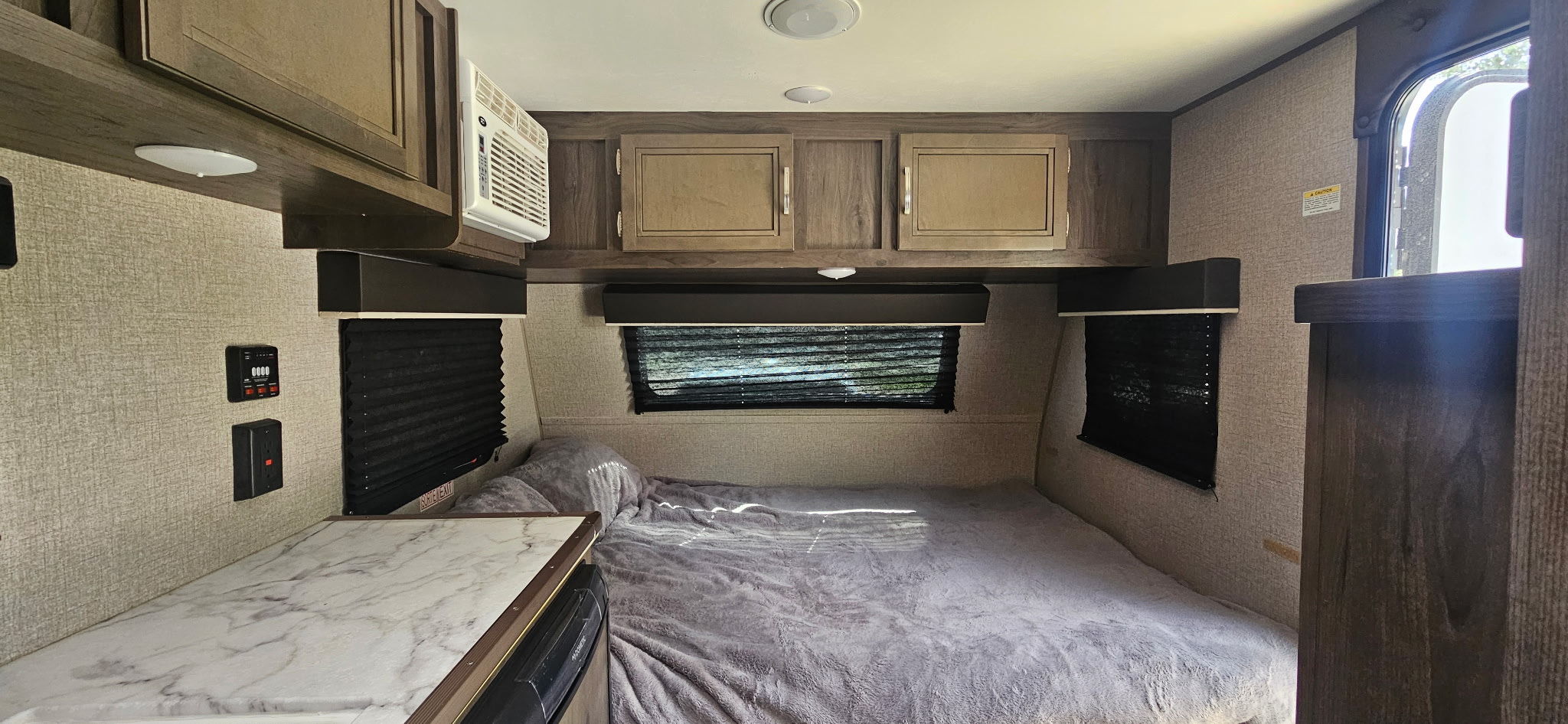 Cozy RV rental bedroom interior with a soft bed, overhead cabinets, AC unit, and window blinds.. Jayco Jay Flight SLX 2020