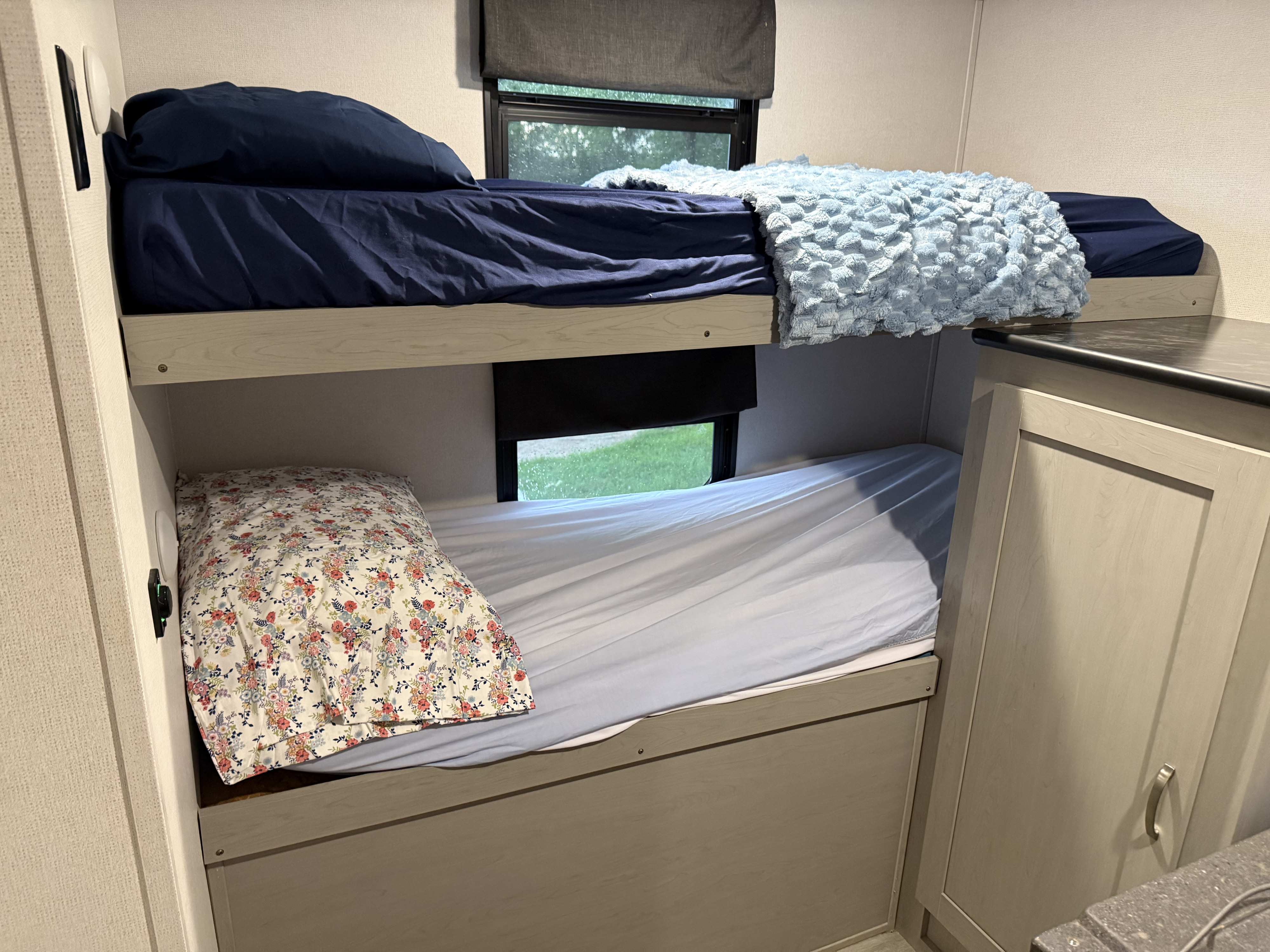 Cozy RV rental bunk beds with comfortable bedding and outdoor views, perfect for family camping adventures.. Forest River Tracer 2022