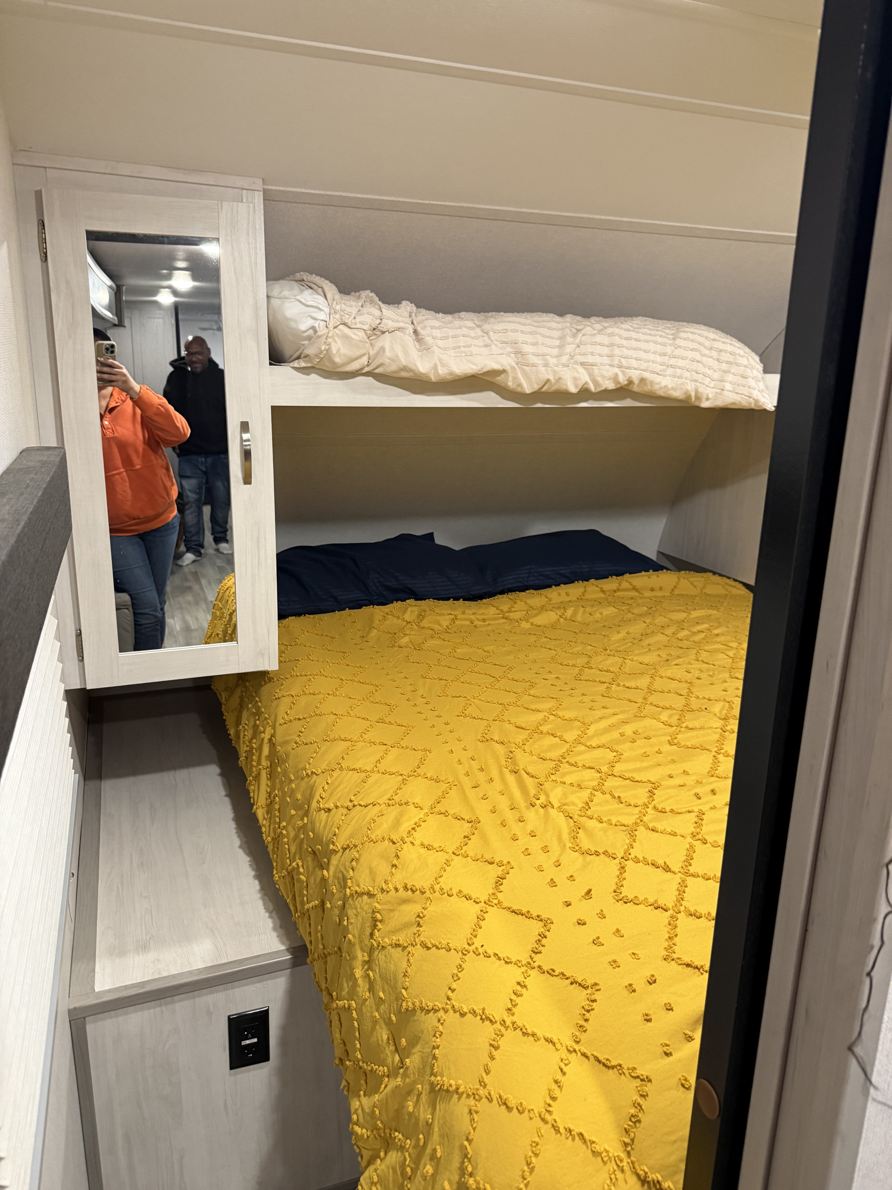 Cozy RV rental bedroom with bright yellow bunk beds and mirrored cabinet. Compact sleeping space ideal for travel.. Forest River Tracer 2022