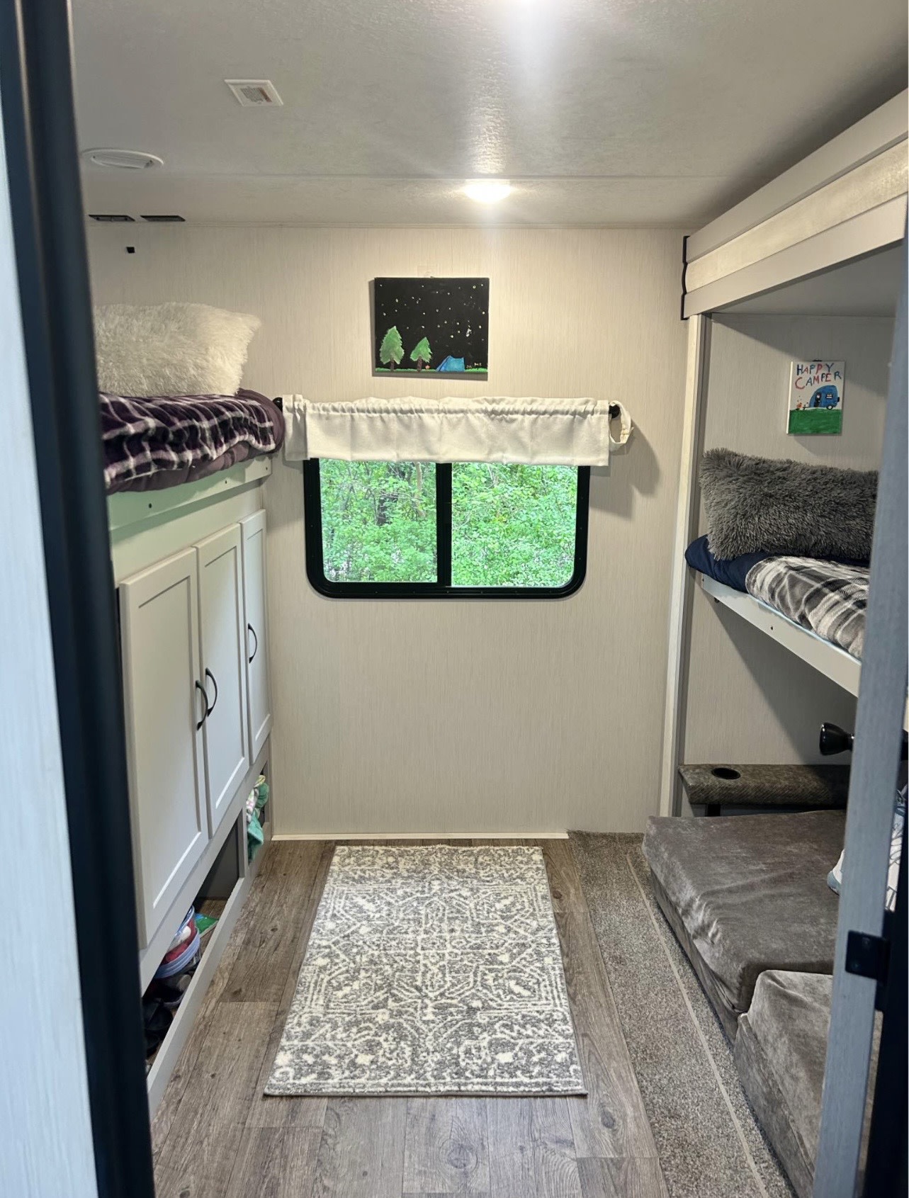 Bright RV rental bunkhouse interior with wood floors, comfy bunks, ample storage, & green views.. Forest River Vibe 2021