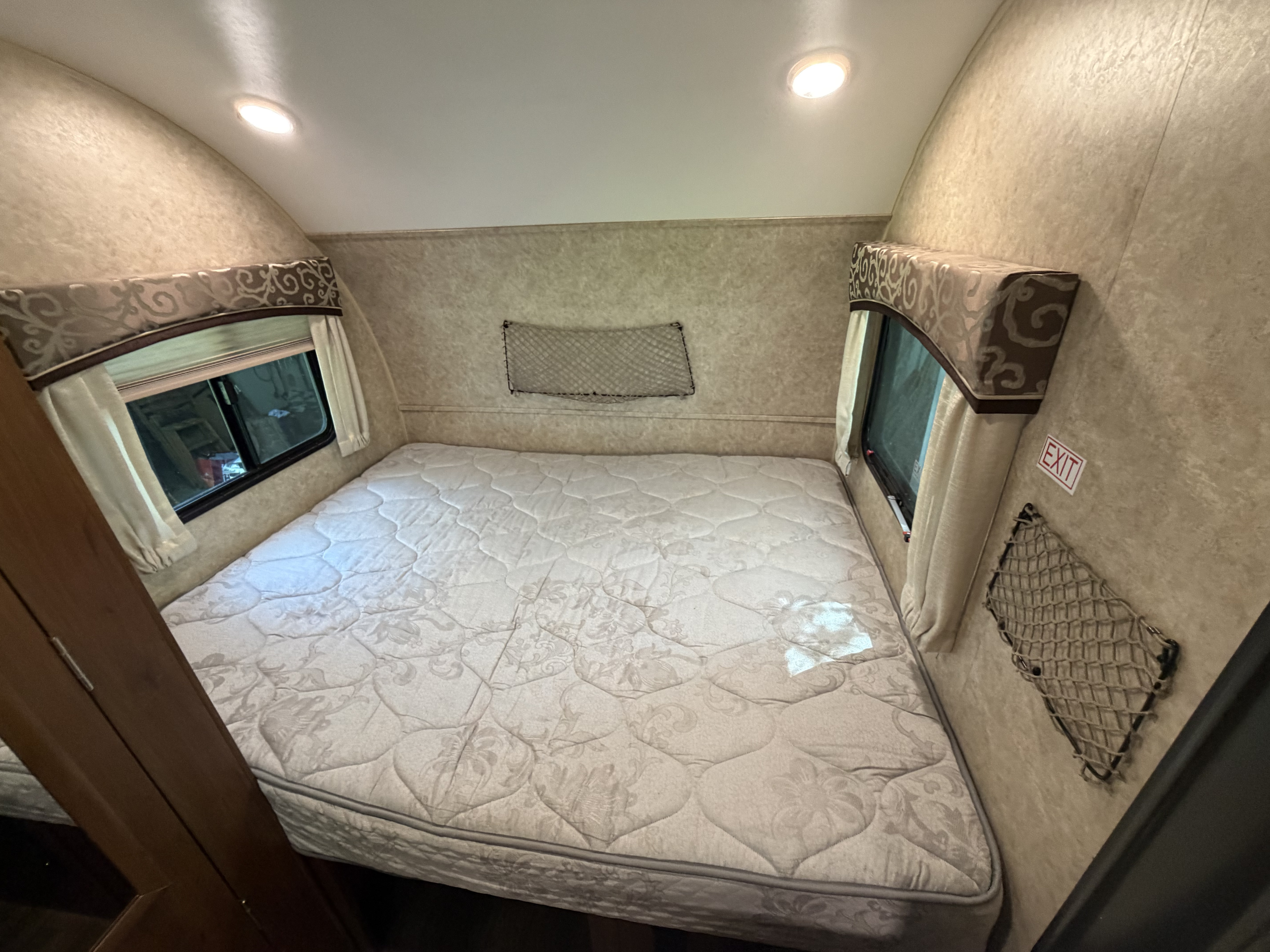 Cozy RV rental bedroom with a comfy mattress, windows, and practical storage nets, ideal for your next adventure.. Jayco Hummingbird 2017