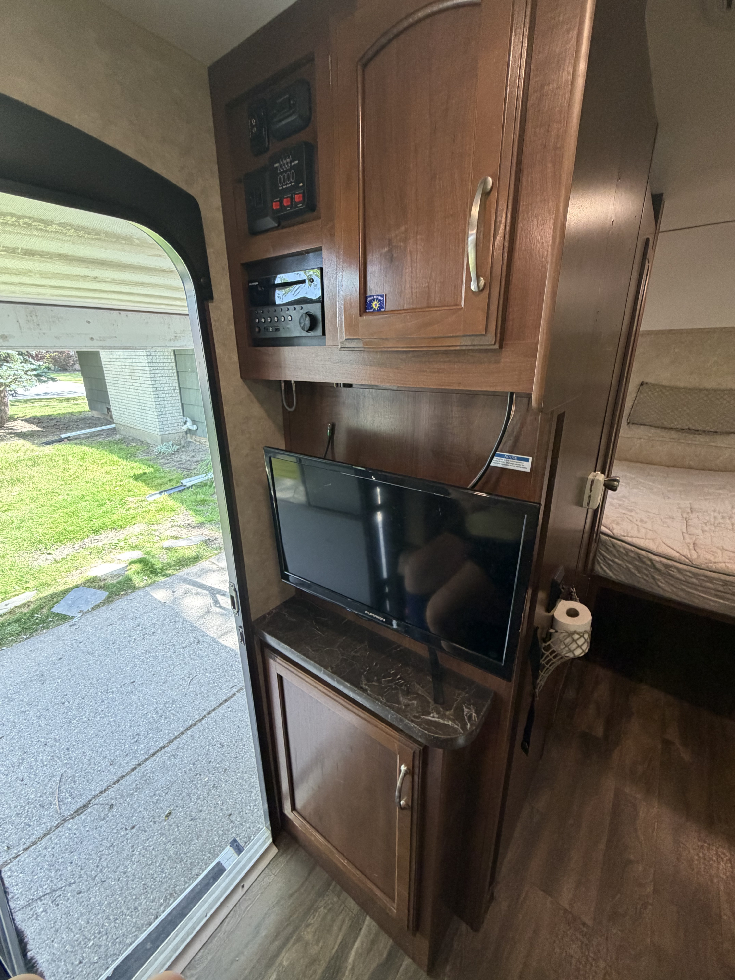 RV rental living area featuring an entertainment system with TV, control panel, and a nearby bedroom.. Jayco Hummingbird 2017