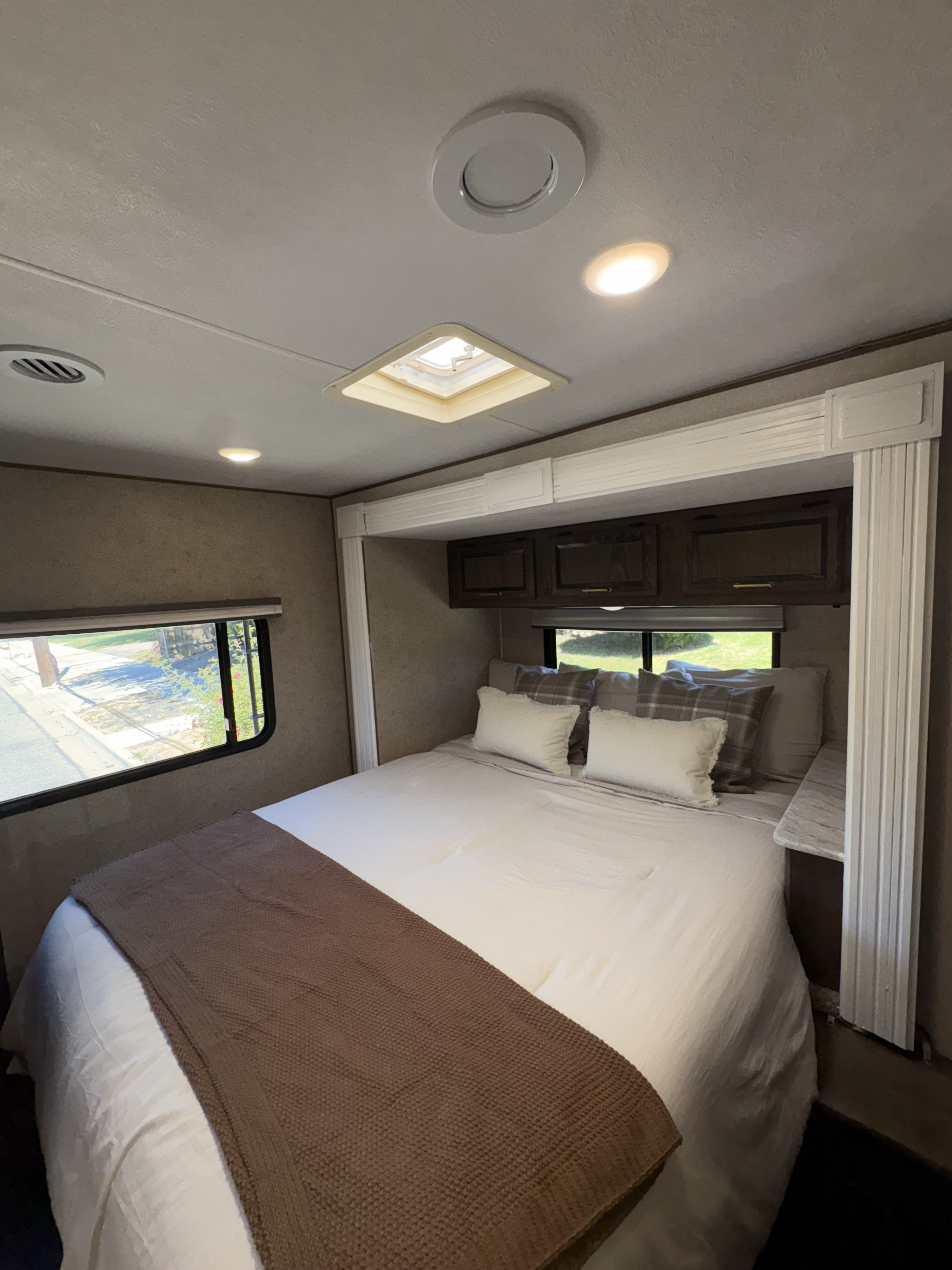 Cozy rv rental bedroom with a neatly made bed, ample storage, ceiling lights, and a window offering a view outdoors.. Coachmen Freelander 2018