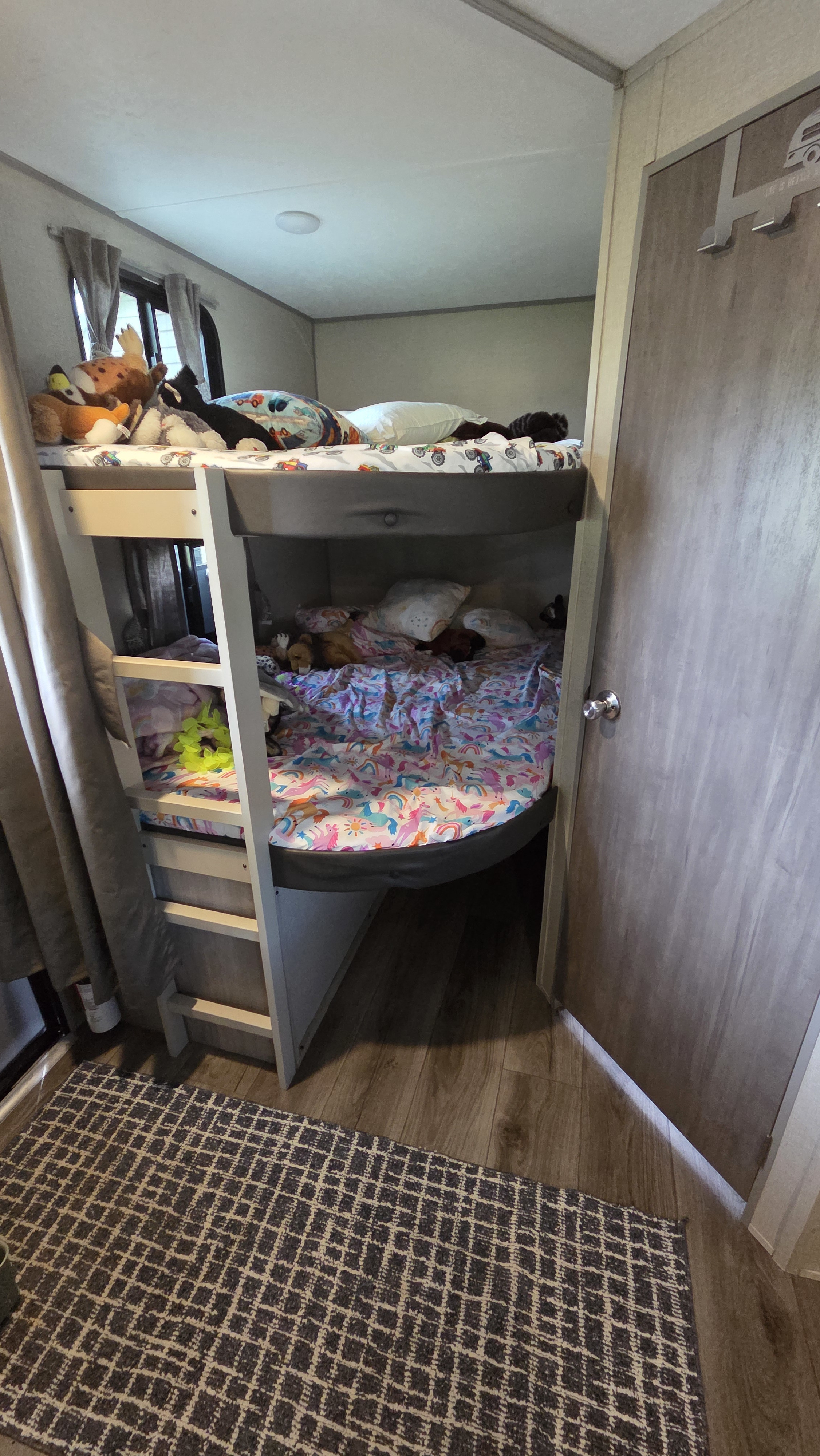 Bunk beds in an rv rental, adorned with plush toys and colorful bedding, offer a cozy sleeping space for kids.. Forest River Coachmen Catalina Legacy 2022