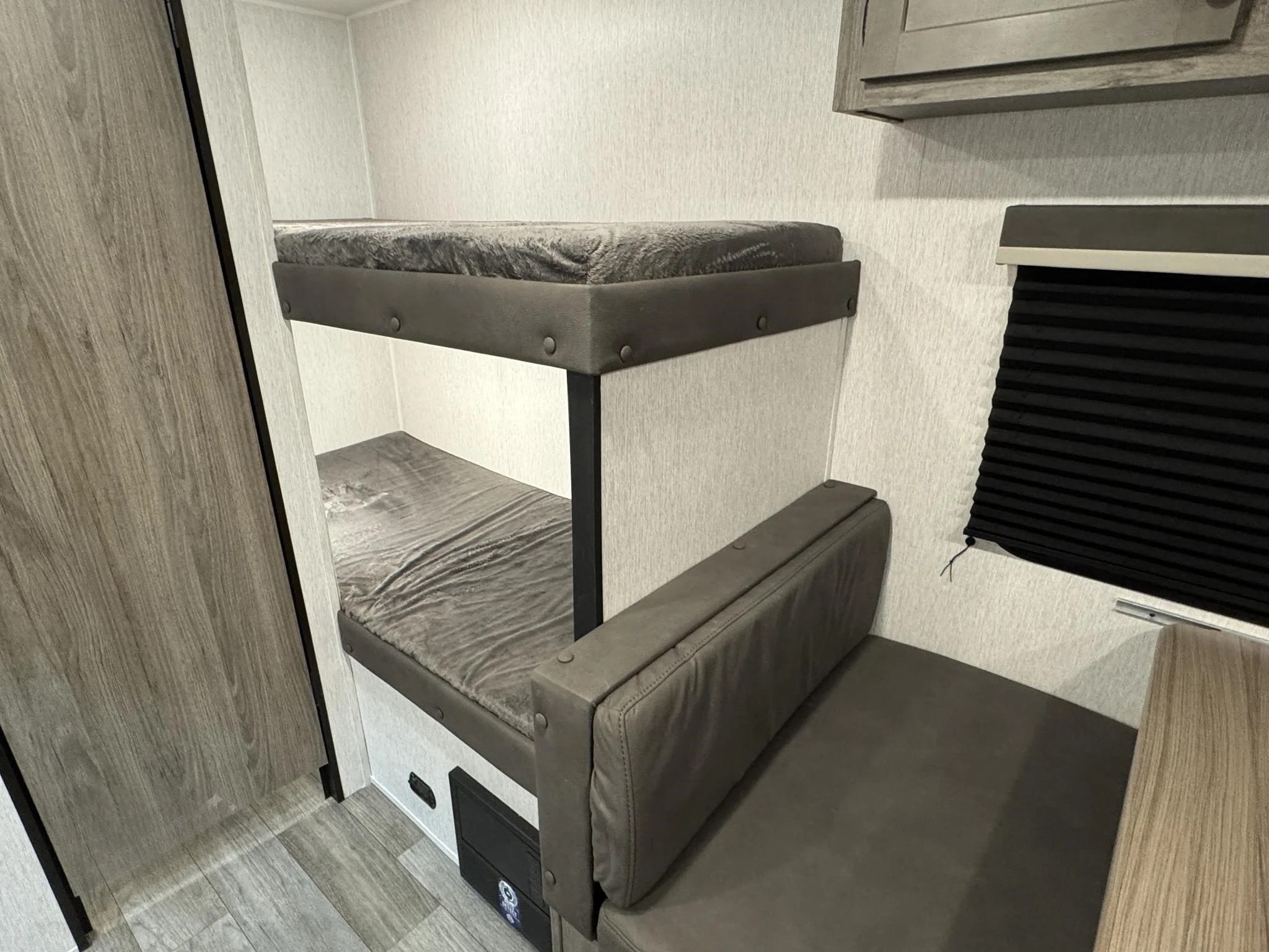 This RV rental's interior boasts space-saving bunk beds and a comfy gray dinette, perfect for your camper journey.. Sunset Park RV Sun Lite LTD 2024