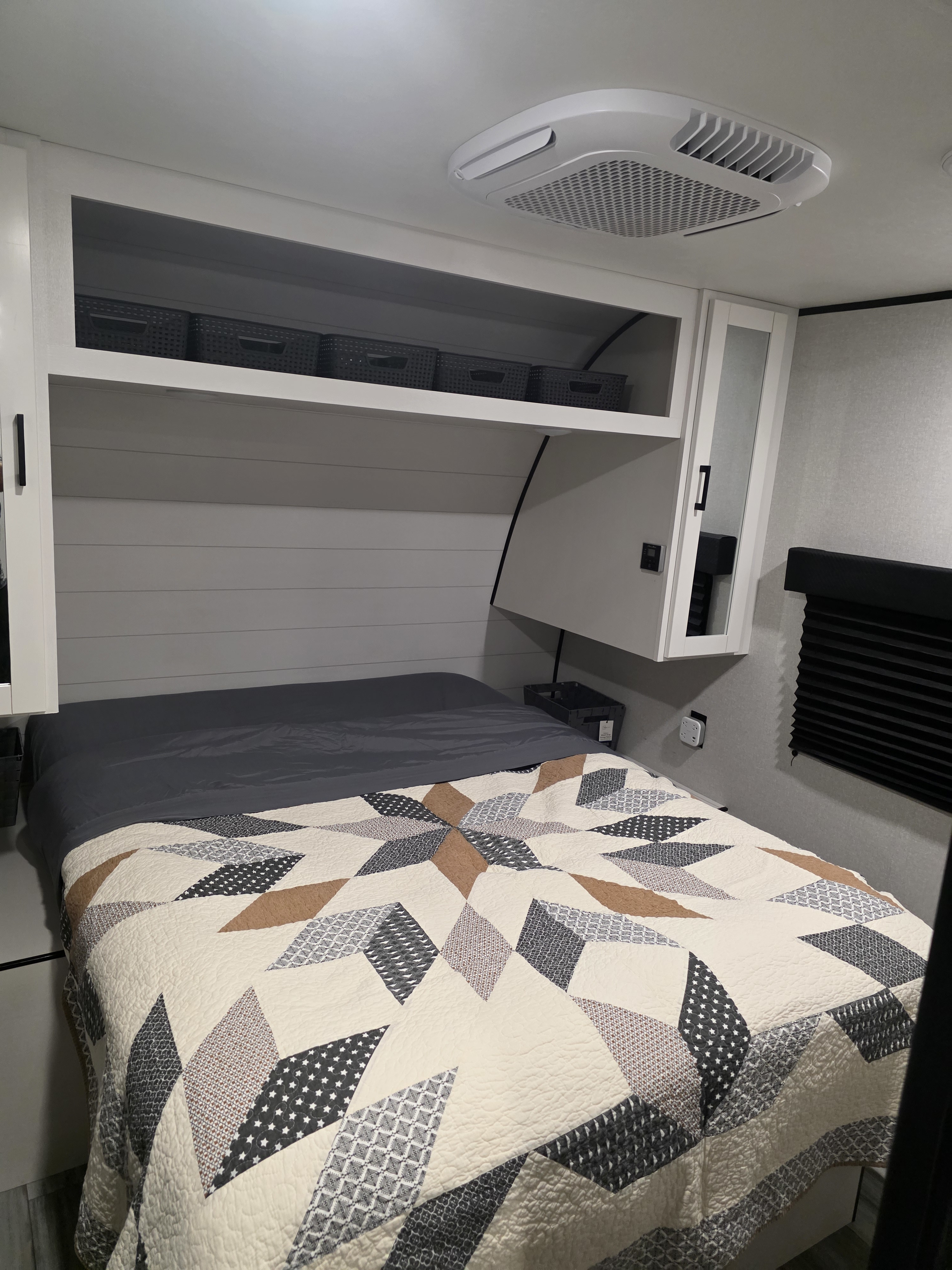 Comfortable RV rental bedroom featuring a patterned quilt, overhead storage, and AC for a relaxing trip.. JAYCO JAY FLIGHT SLX 2026