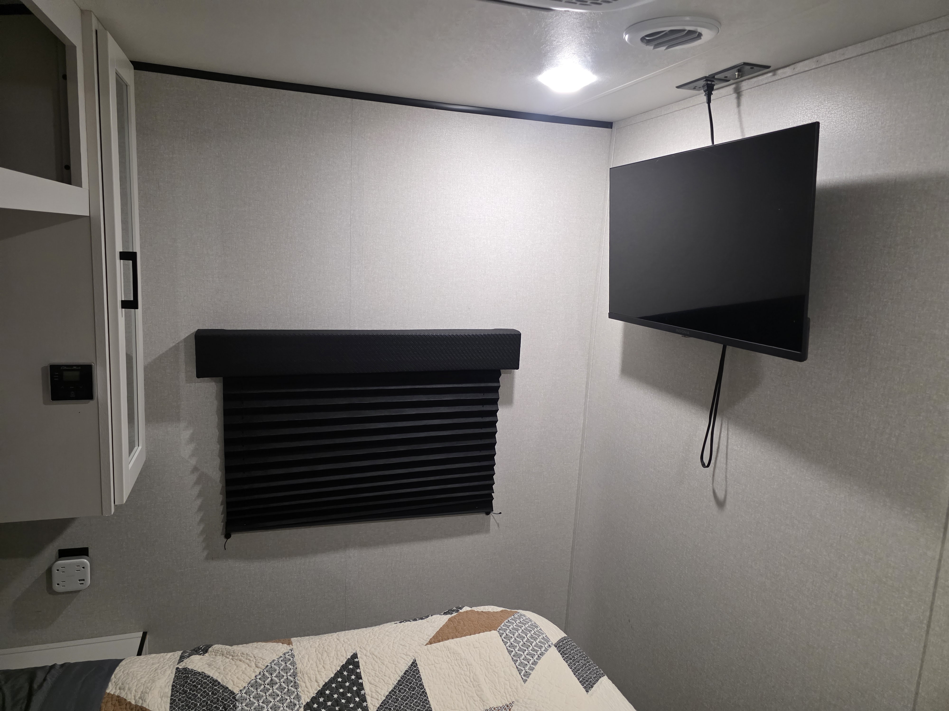 RV rental bedroom interior. Features a mounted TV, pleated window shade, smart thermostat, and power outlet over a cozy bed.. JAYCO JAY FLIGHT SLX 2026