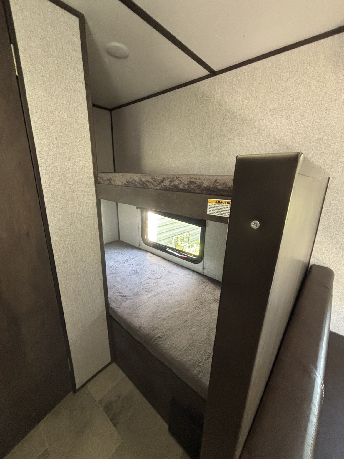 Compact bunk beds in an RV rental, offering sleeping space for campers. Features a window on the lower bunk.. Dutchmen Coleman Lantern LT 2021