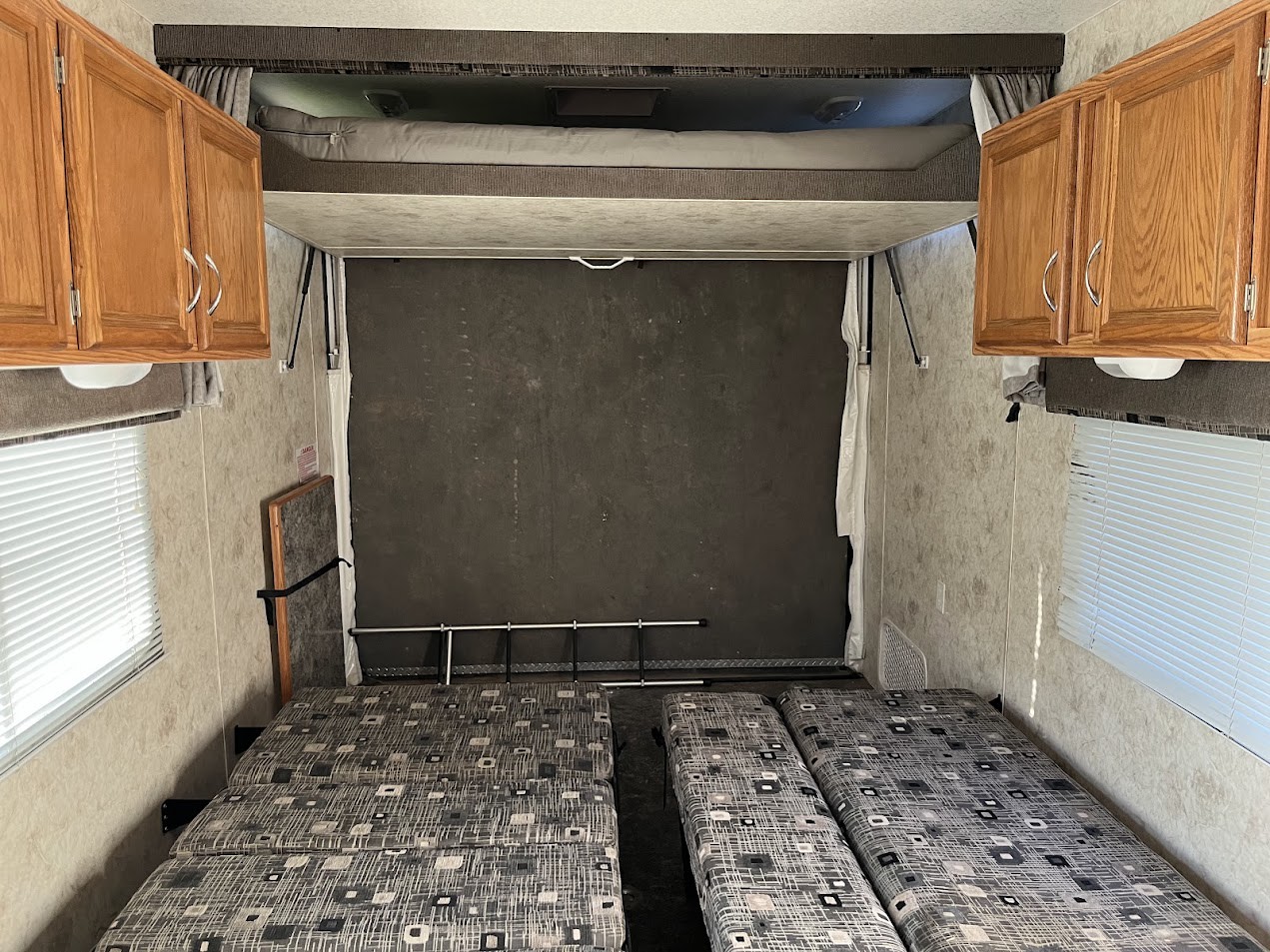 RV rental toy hauler interior: lower convertible beds, upper bunk bed, rear ramp wall, & wood cabinets. Ready for travel!. Eclipse Recreational Vehicles Attitude 2007