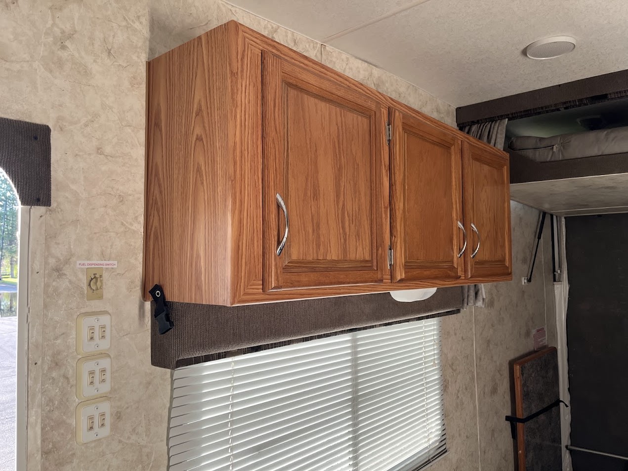 Interior of an RV rental: wooden cabinets, window blinds, and control panel with a fuel dispensing switch.. Eclipse Recreational Vehicles Attitude 2007
