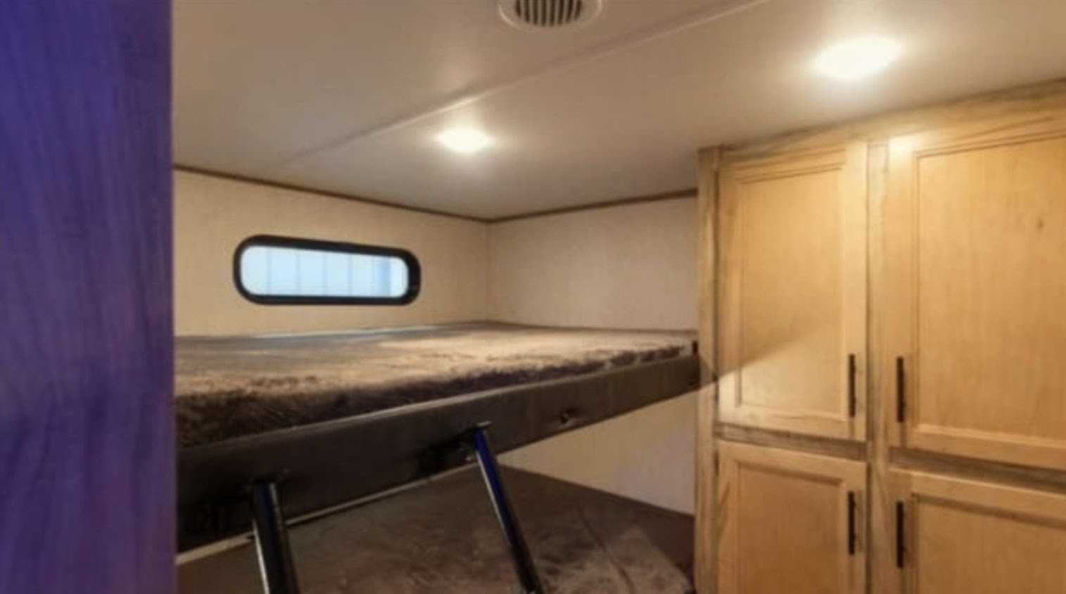 Cozy RV rental interior with bunk beds, an oval window, and wooden cabinets for comfortable sleeping.. Forest River Alpha Wolf 2021