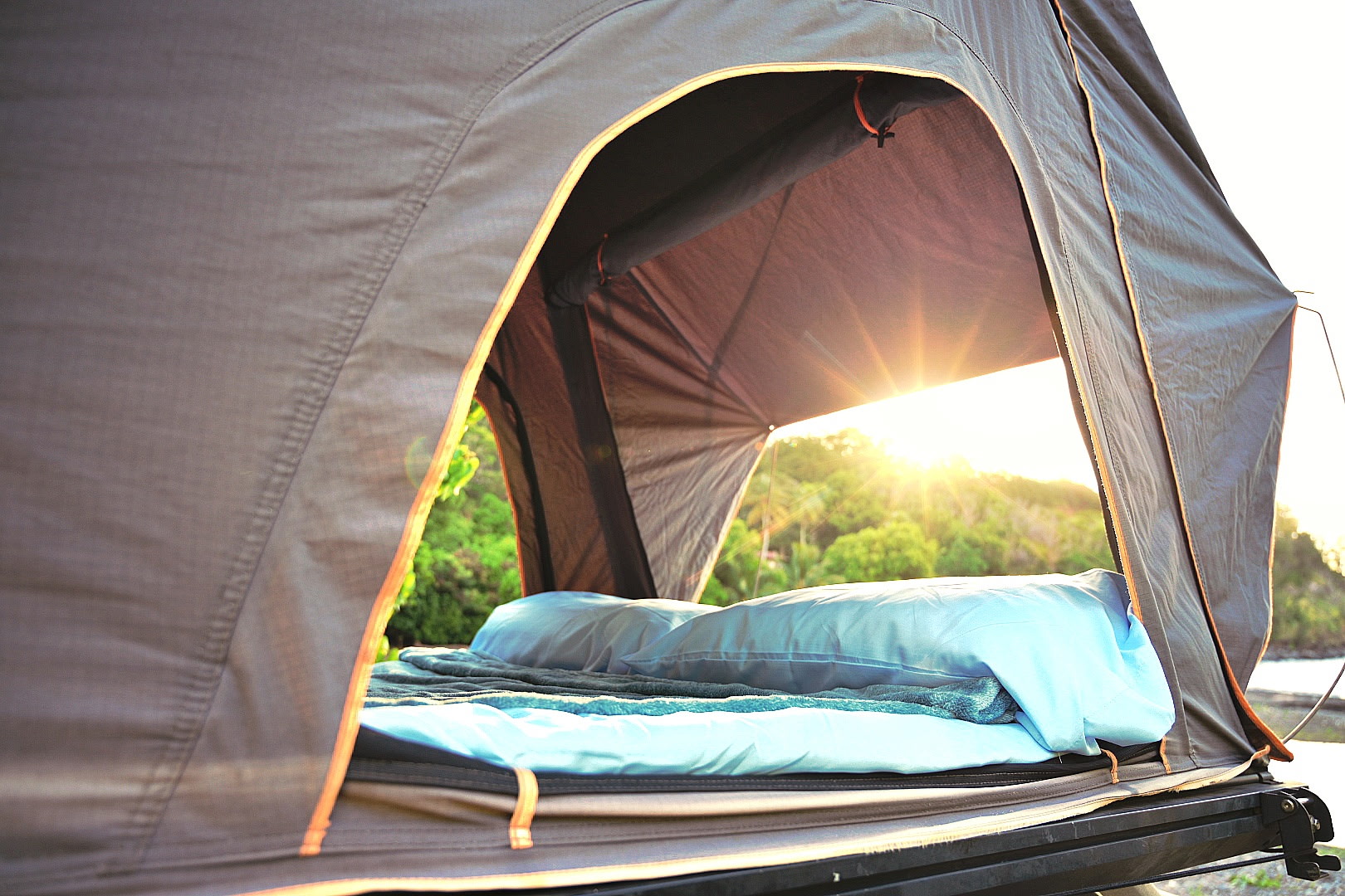 RV rental rooftop tent's comfy bed, open to a stunning sunrise/sunset view over a green landscape. Ideal for camping.. Subaru Outback 2017