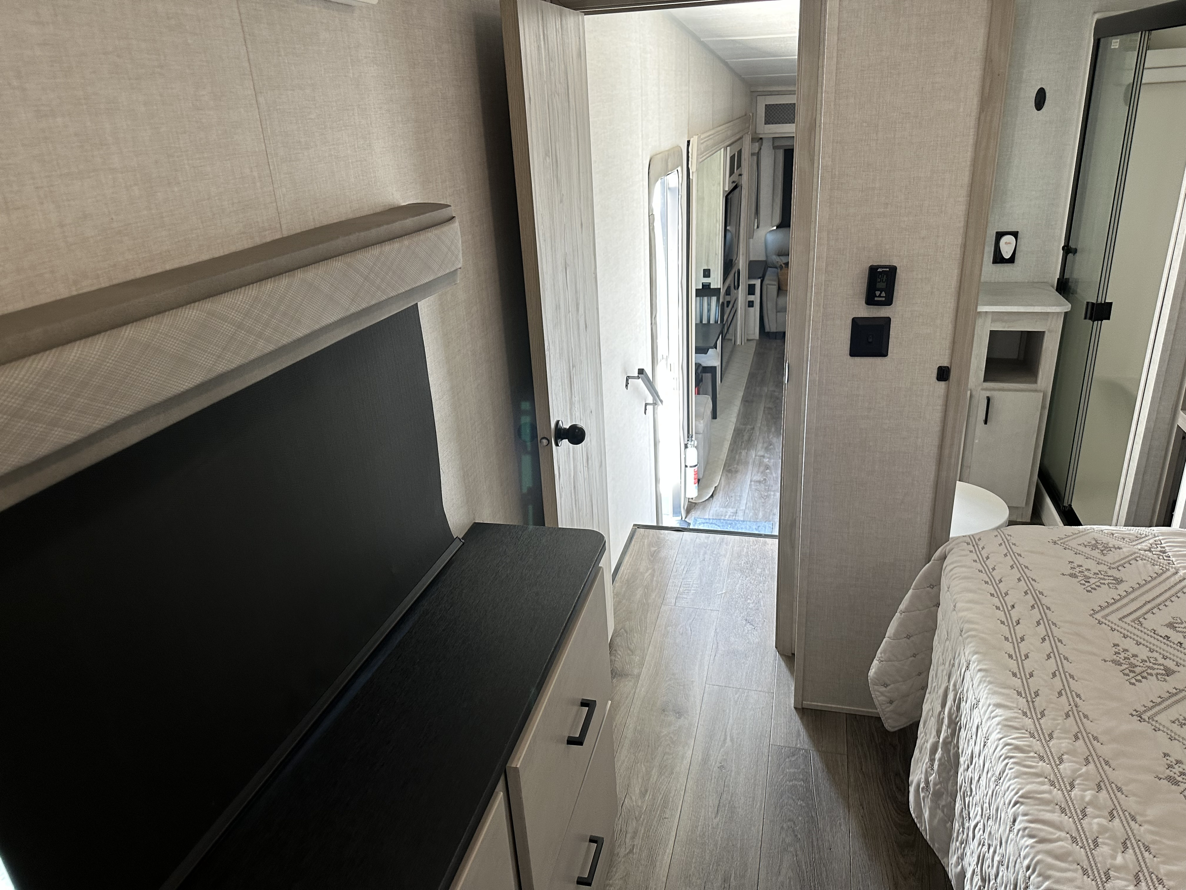 Modern RV rental interior with bedroom, hallway, and bathroom access. Light wood floors and neutral decor.. East to West Tandara 2022