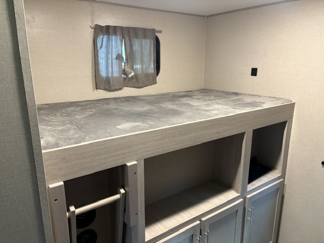 RV rental bunk bed with gray mattress, built-in storage cubbies & cabinets, plus a ladder. Bright, functional camper interior.. Coachmen Catalina 2022