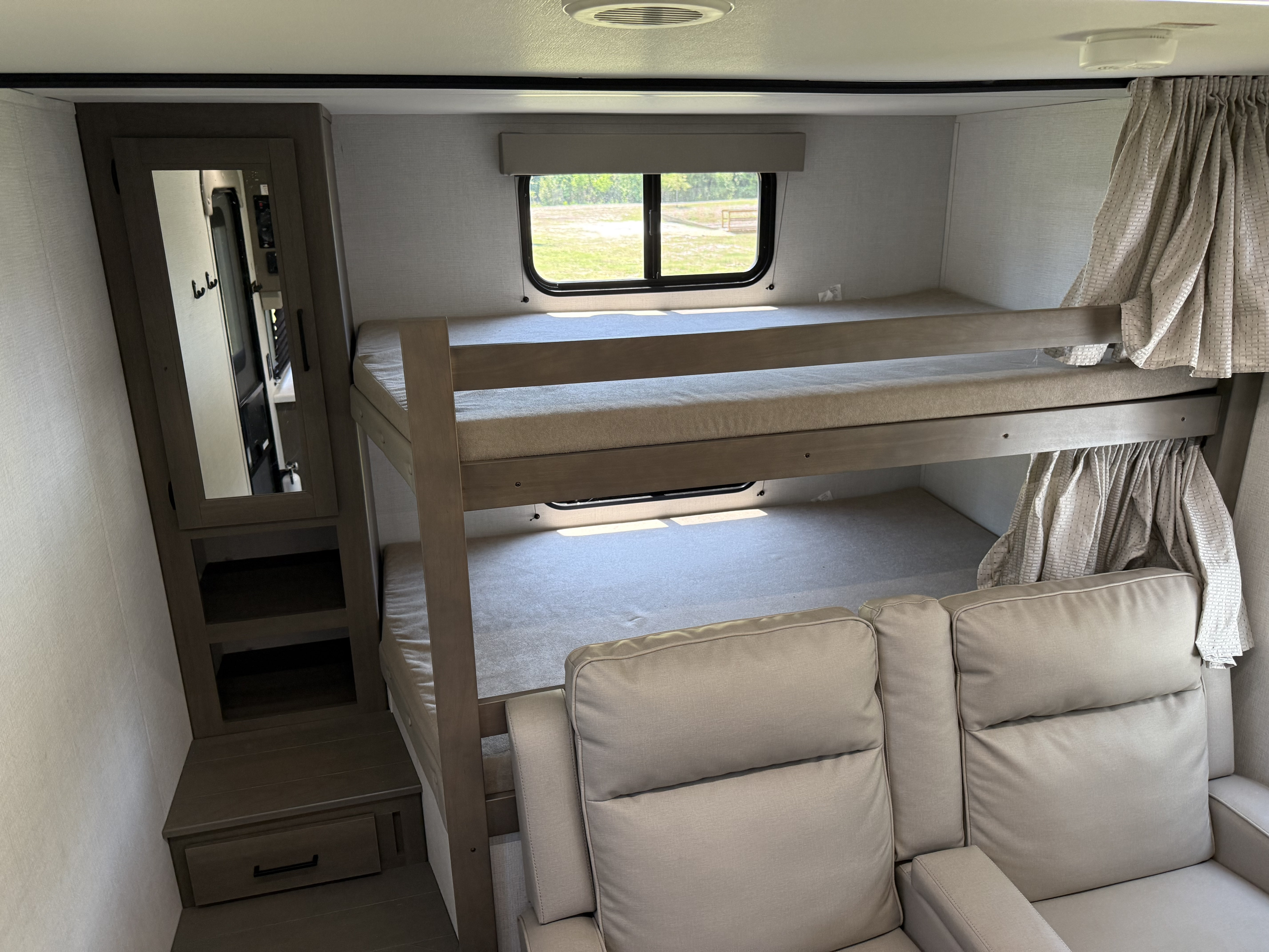 RV rental interior showing functional bunk beds, a window, and storage for a compact, comfortable sleeping area.. Grand Design Transcend 2025