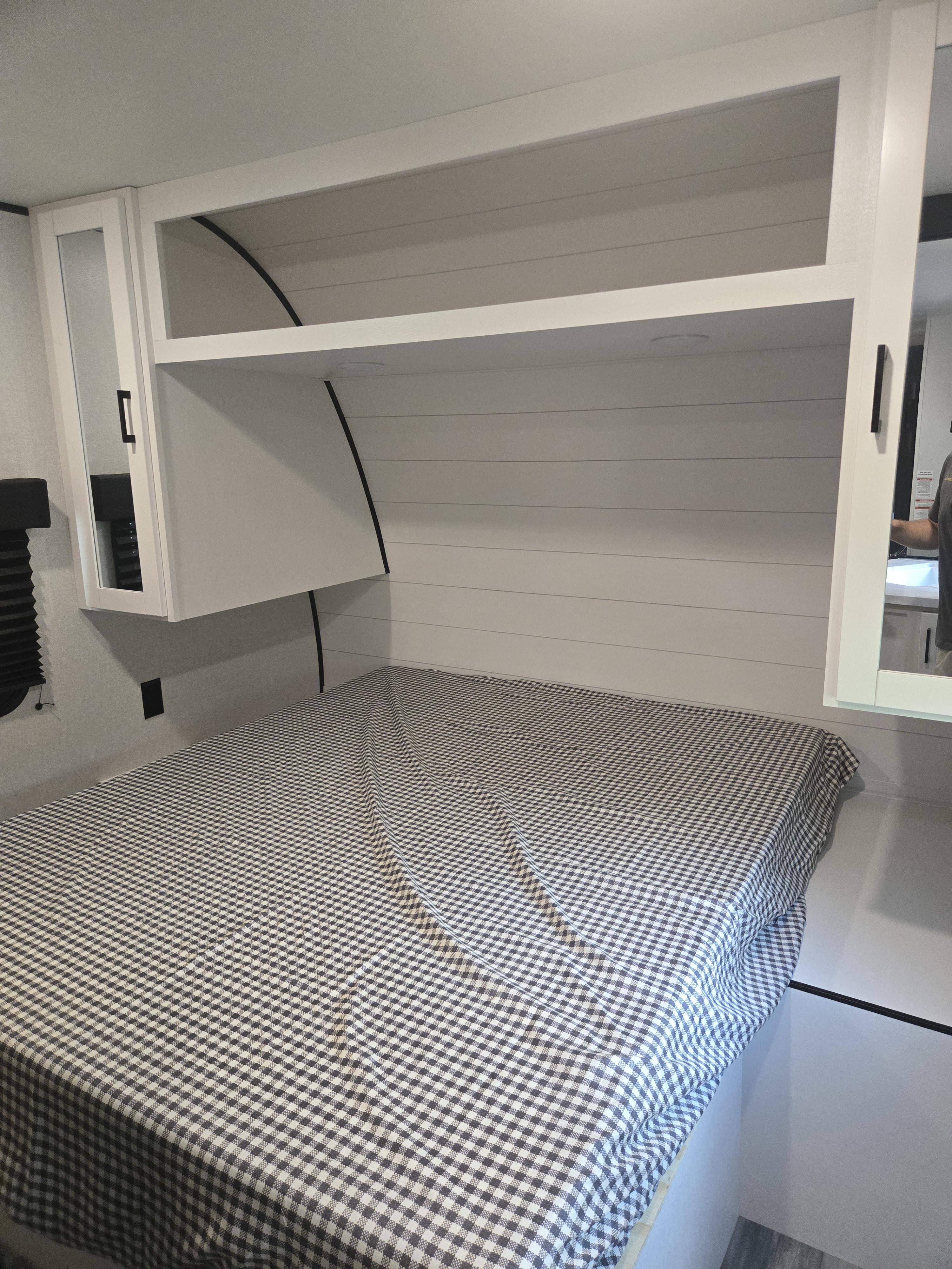 RV rental bedroom showcasing a comfy checkered bed, white shiplap walls, and built-in overhead storage.. Jayco Jay Flight SLX 2026