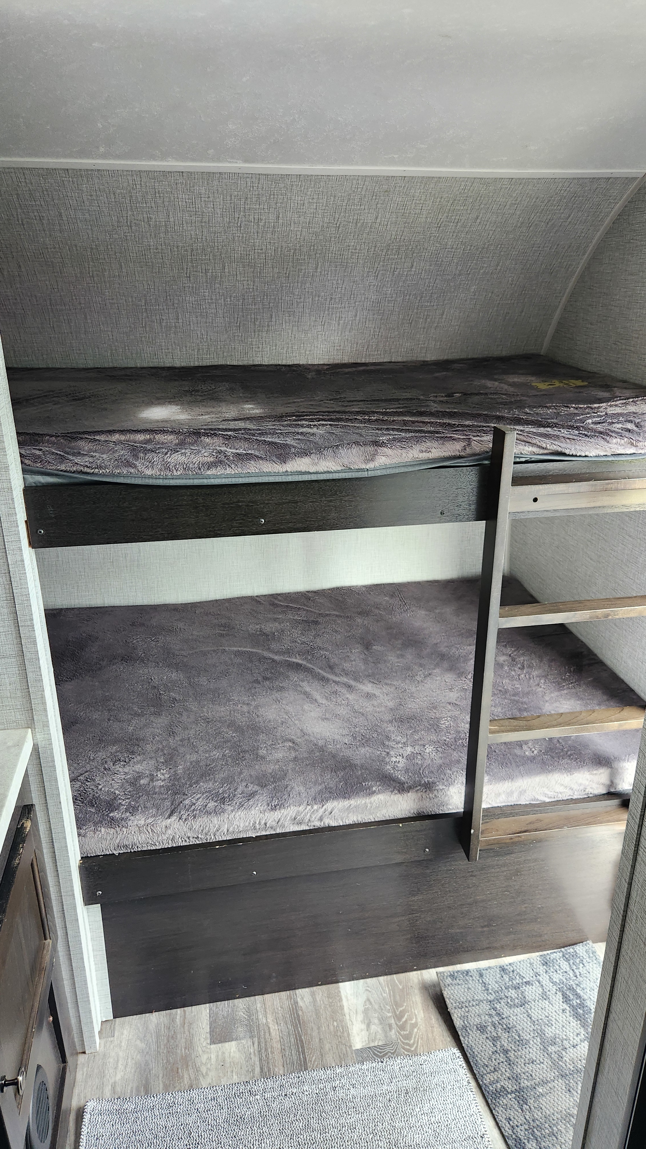This RV rental features cozy bunk beds with soft grey bedding, a sturdy ladder, and wood-look flooring.. Braxton Creek Bushwhacker Plus 2021