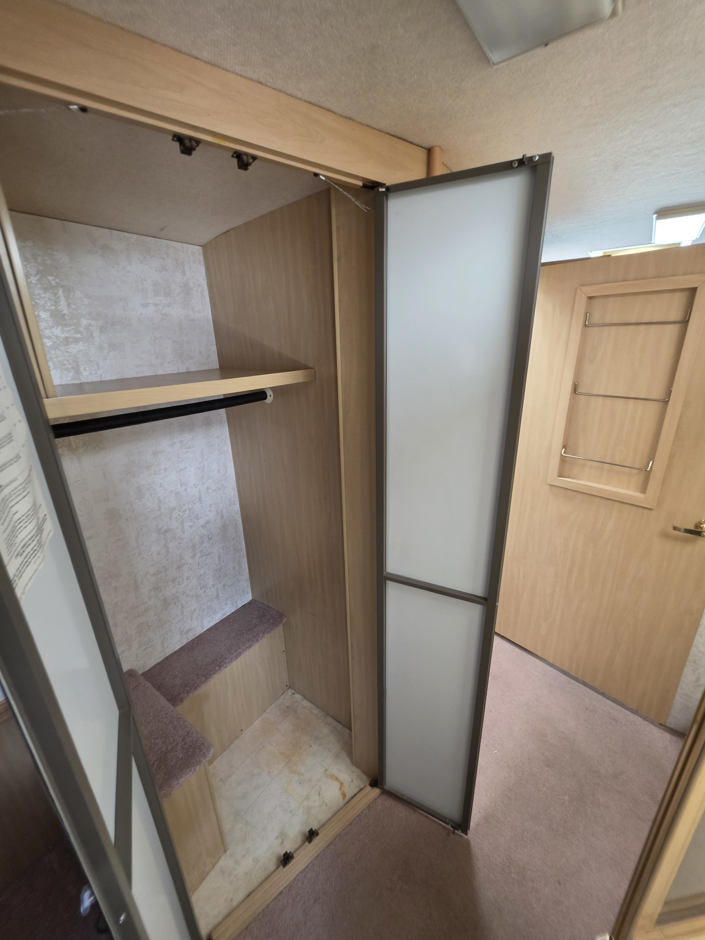 RV rental interior: Open wardrobe with shelf, hanging rod, and carpeted step. Compact storage solutions for your camper adventure.. Winnebago Itasca Sunova 1998