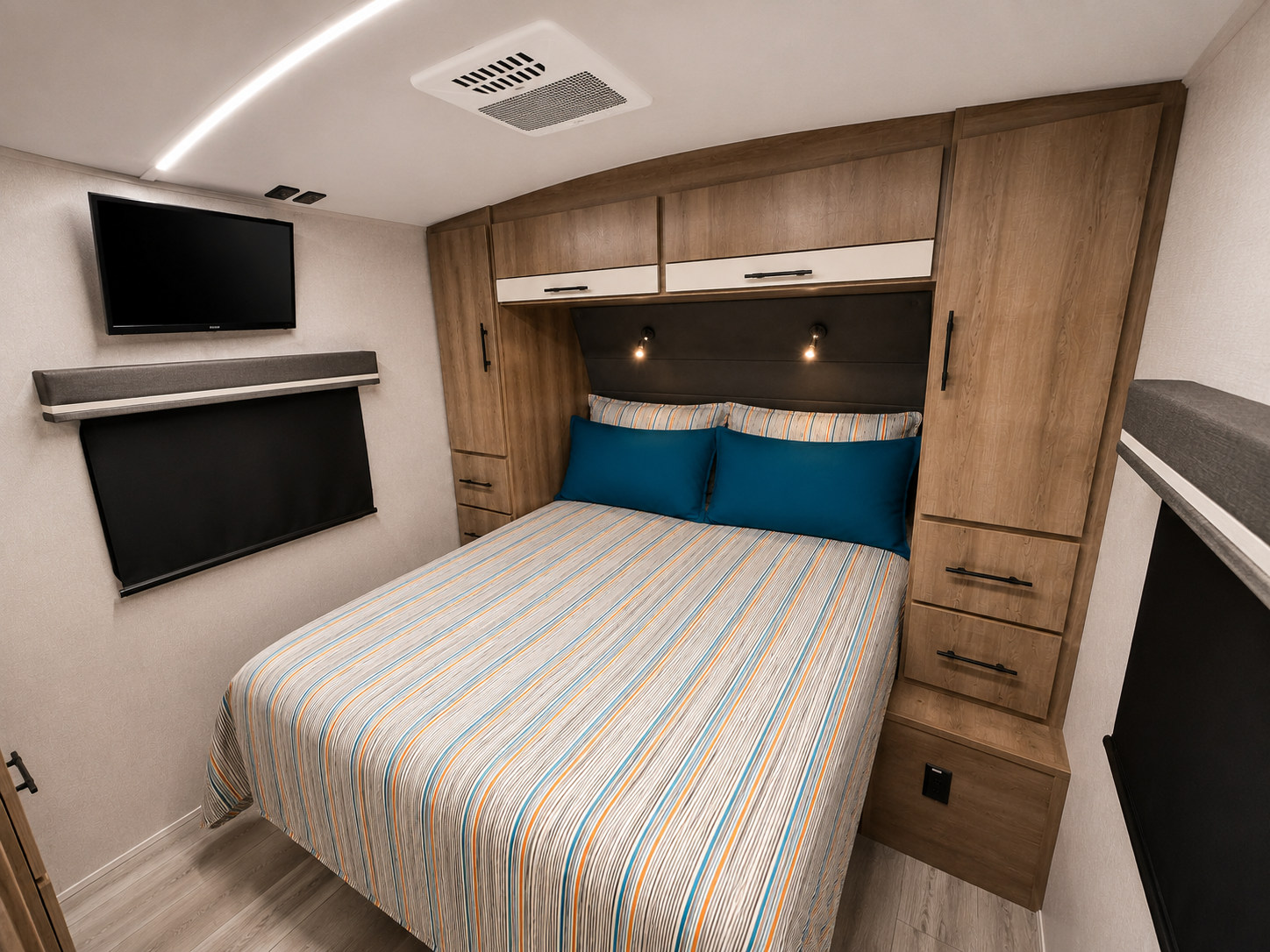 This cozy RV rental bedroom features a comfortable bed with storage, a wall-mounted TV, and a window for mobile living.. Grand Design Imagine 2024