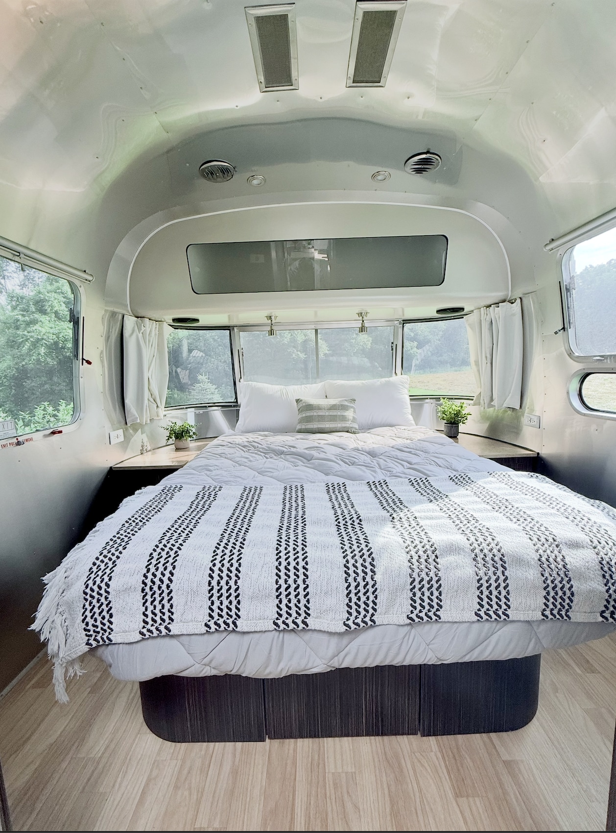 Cozy Airstream rv rental bedroom with a large bed, white linens, and scenic views. Ideal for a serene getaway.. Airstream International 2018