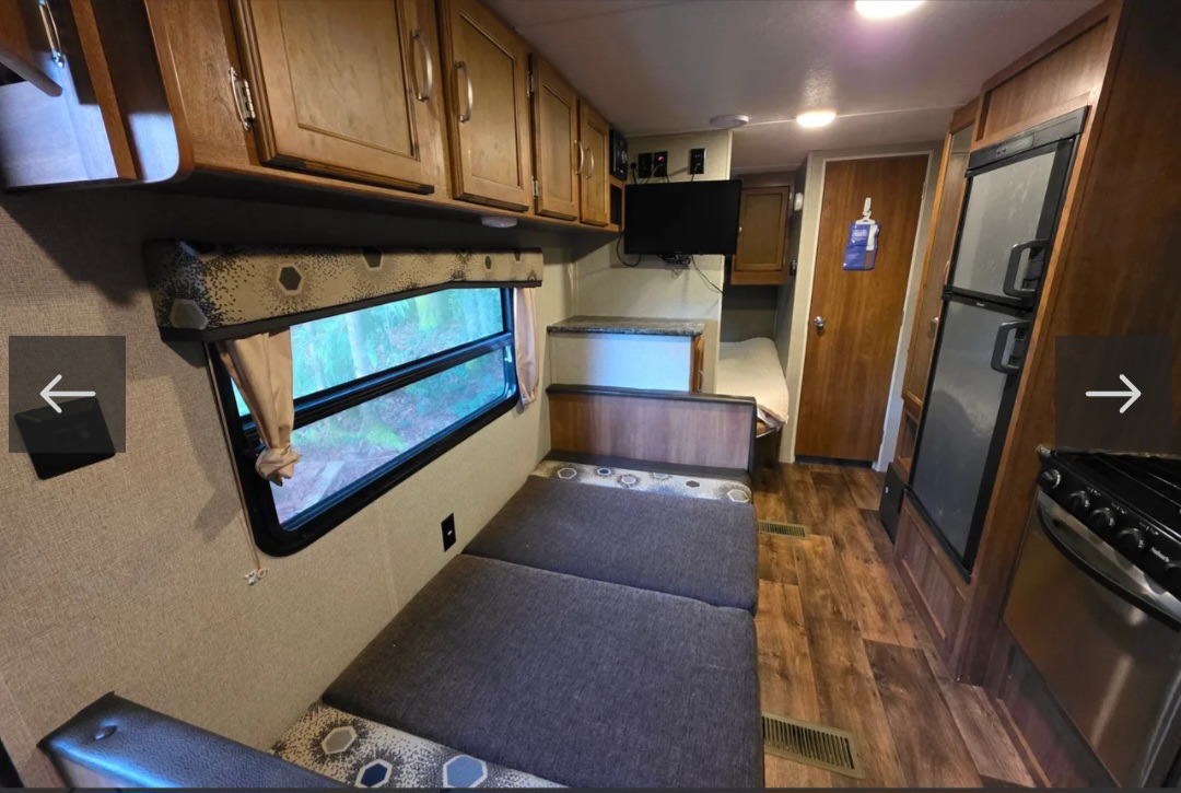 This RV rental interior features a convertible dinette, kitchen with fridge & stove, overhead cabinets, and a bunk bed.. Keystone RV Springdale 2017