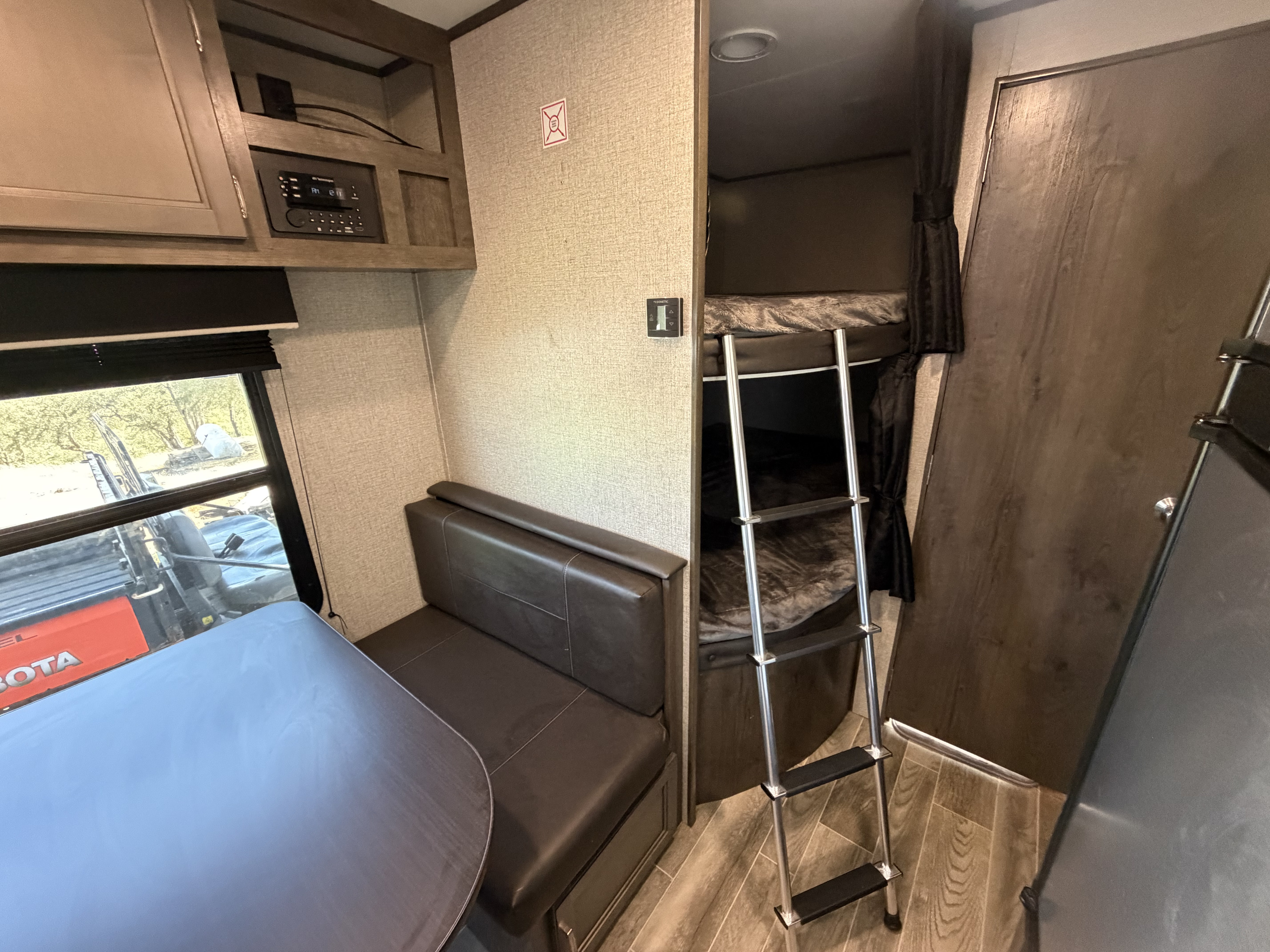 Cozy RV rental interior featuring a dinette, overhead media center, and bunk beds with a ladder for comfortable travel.. Jayco Jay Flight SLX 2021