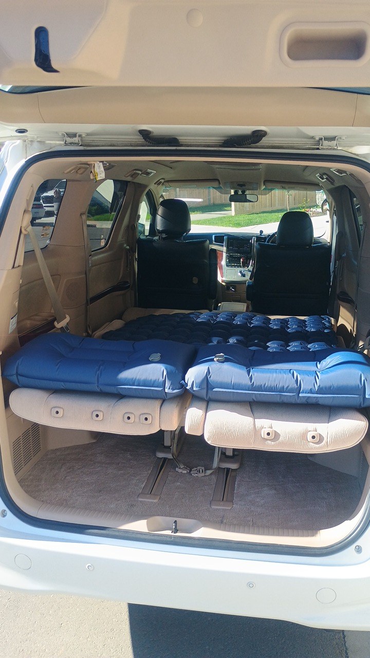 RV rental car camping setup: blue inflatable mattresses fill the back of a spacious minivan, ready for adventure.. Toyota HIACE CAMPERVAN 2010