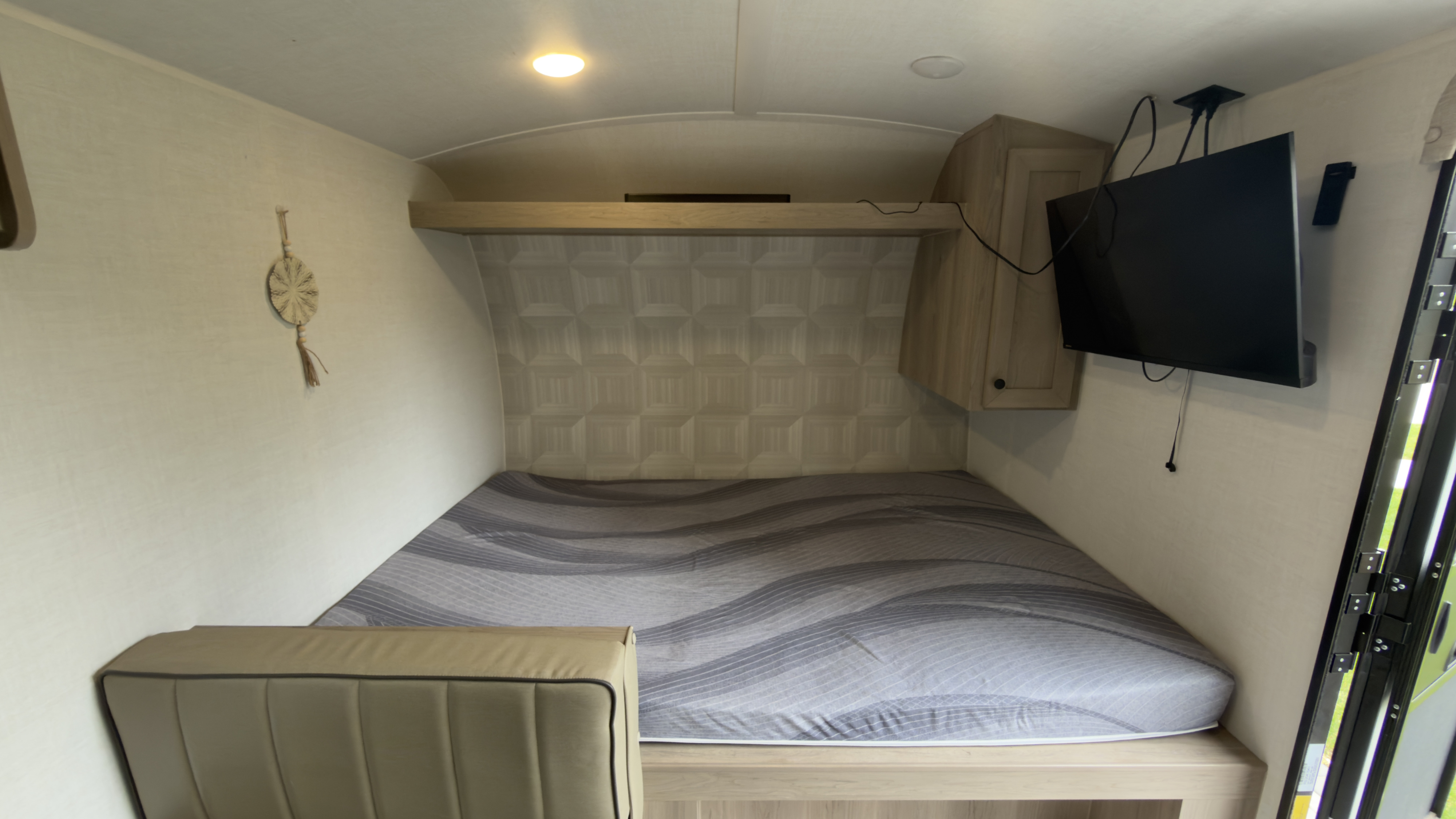Cozy RV rental bedroom features a gray mattress, bench seating, overhead storage, and a wall-mounted TV.. Forest River Rockwood Geo Pro G17 LE 2026