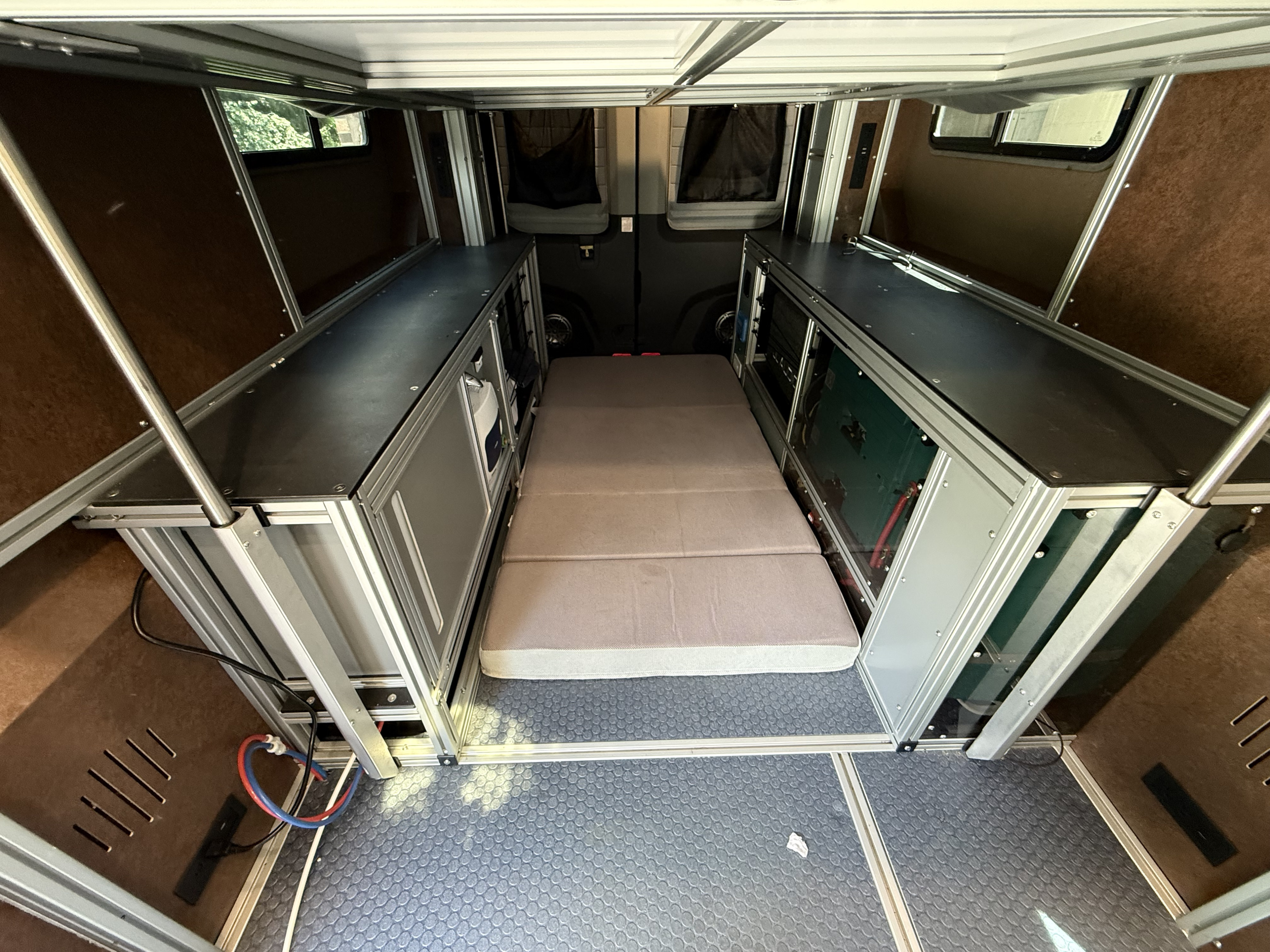 Explore this RV rental's modular camper van interior. Features a comfy bed, integrated storage, and practical utilities.. Ford Transit 2020