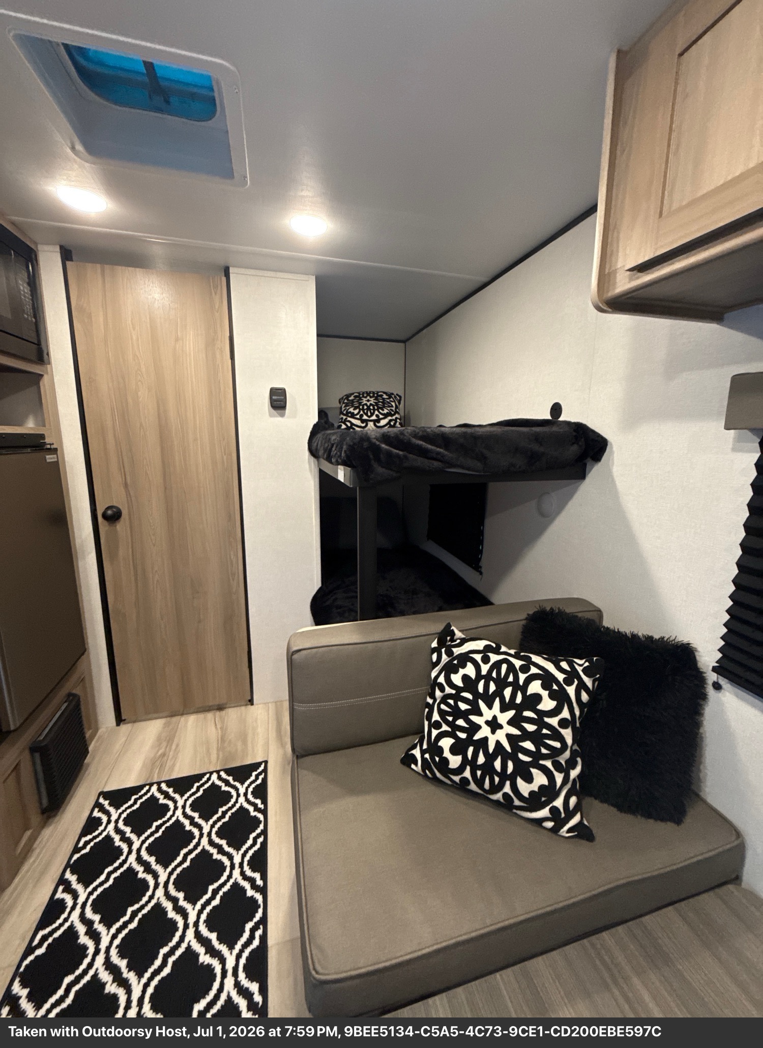 This RV rental interior features modern bunk beds, a comfy sofa, and stylish black & white decor, perfect for travel.. Keystone Coleman 17B 2026